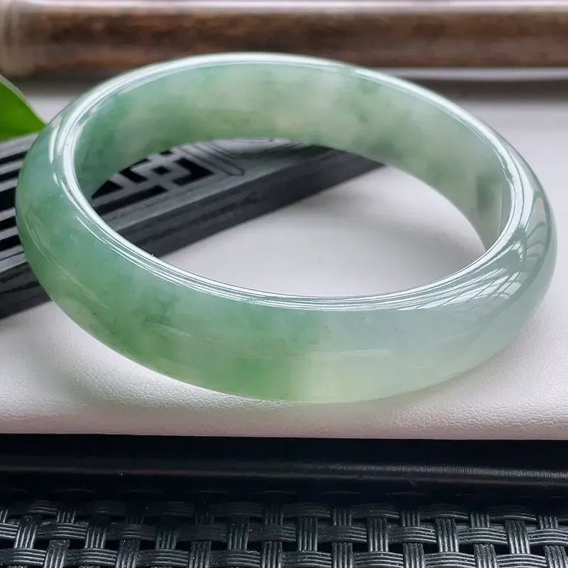 【正圈57.5圈口】自然光实拍，天然翡翠A货水润飘绿平安镯，尺寸：57.5-13.6-7.5mm，重量：57.36g。质地细腻，种水十足，半山半水，特色飘绿花，颜色自然，版型宽厚，十分耐看，上身秀气迷人！