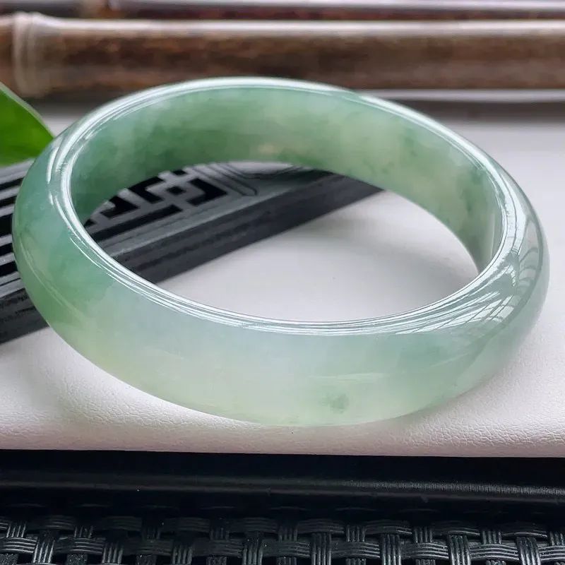 【正圈57.5圈口】自然光实拍，天然翡翠A货水润飘绿平安镯，尺寸：57.5-13.6-7.5mm，重量：57.36g。质地细腻，种水十足，半山半水，特色飘绿花，颜色自然，版型宽厚，十分耐看，上身秀气迷人！