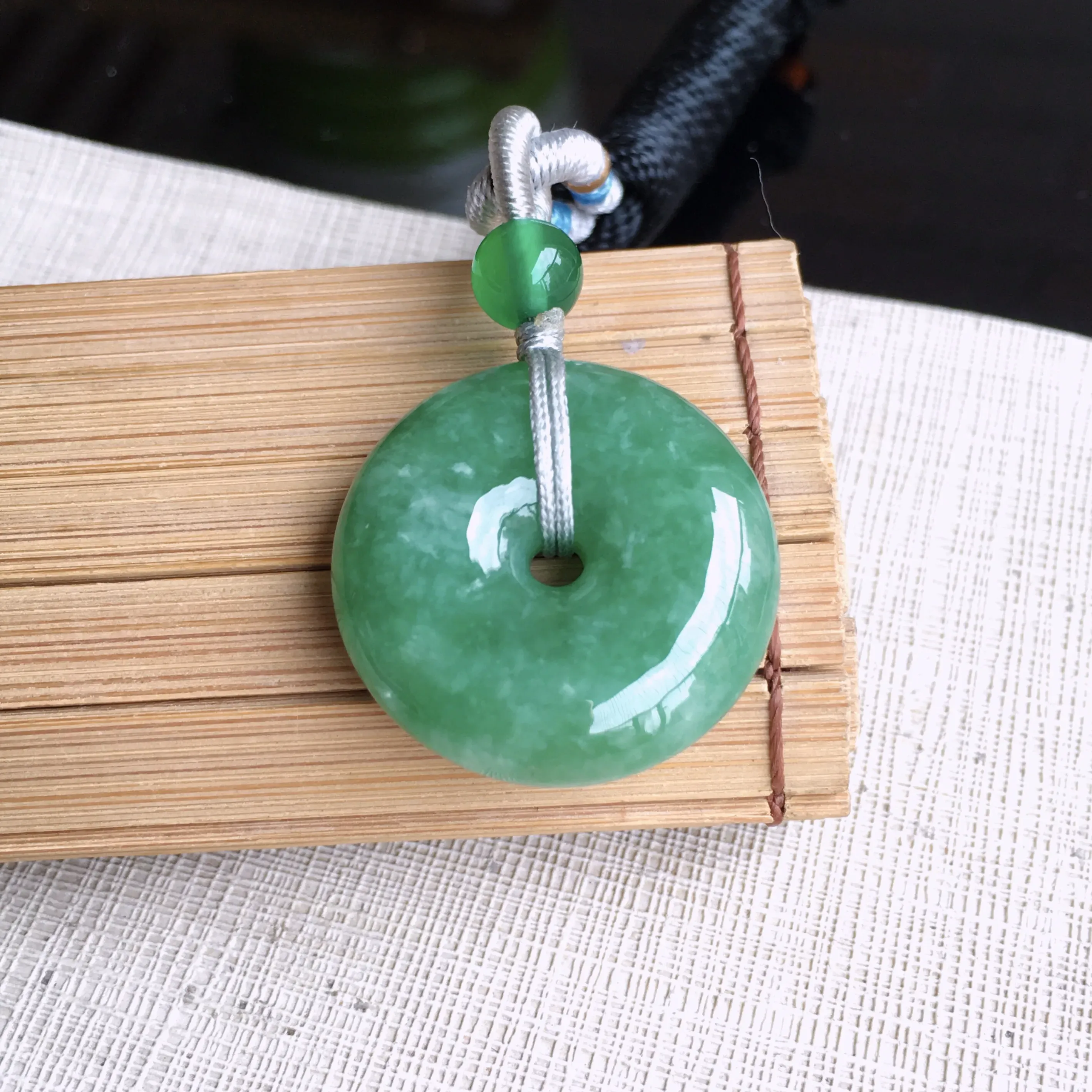 精美满豆绿平安扣吊坠，玉质细润，色泽鲜艳，均匀，饱满厚实，佩戴佳品，尺寸23.8*7.3mm 佩珠顶珠为装饰珠