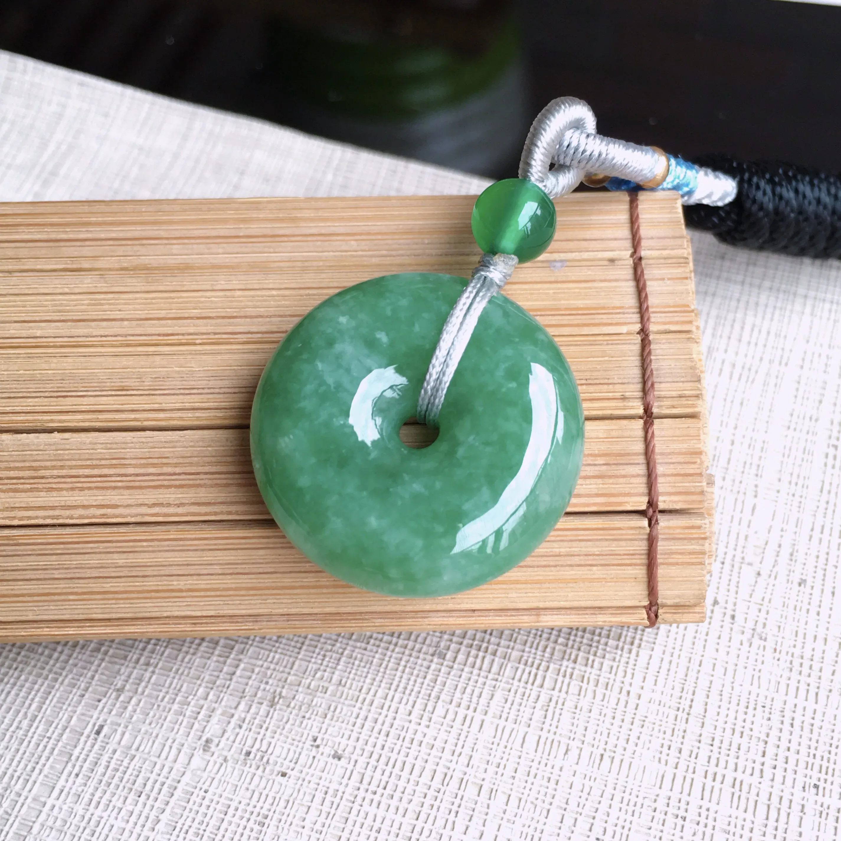 精美满豆绿平安扣吊坠，玉质细润，色泽鲜艳，均匀，饱满厚实，佩戴佳品，尺寸23.8*7.3mm 佩珠顶珠为装饰珠