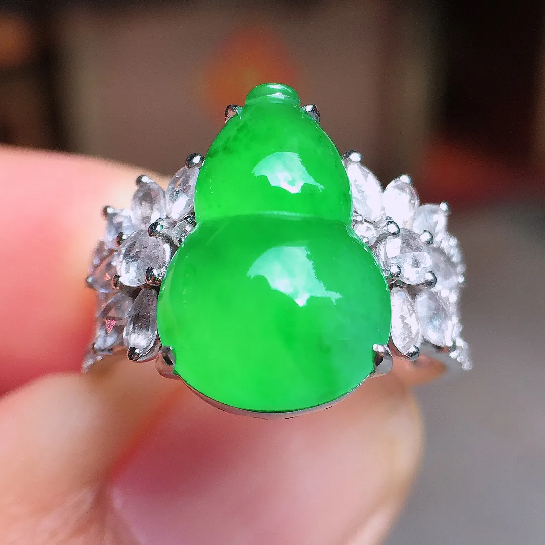 阳绿葫芦戒指，色泽均匀艳丽，玉质细腻，荧光感超
强，饱满水润，气质满满。18k
金豪华镶嵌