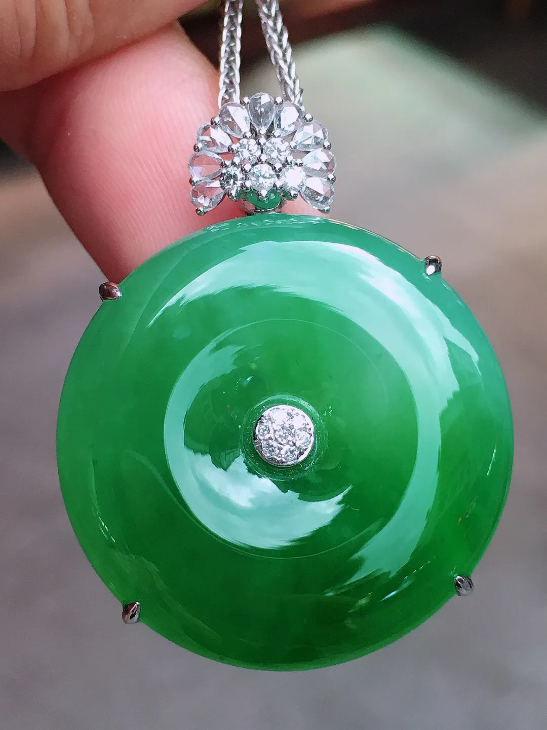 阳绿平安扣吊坠，色泽均匀艳丽，玉质细腻，荧光感超
强，饱满水润，气质满满。18k
金豪华镶嵌