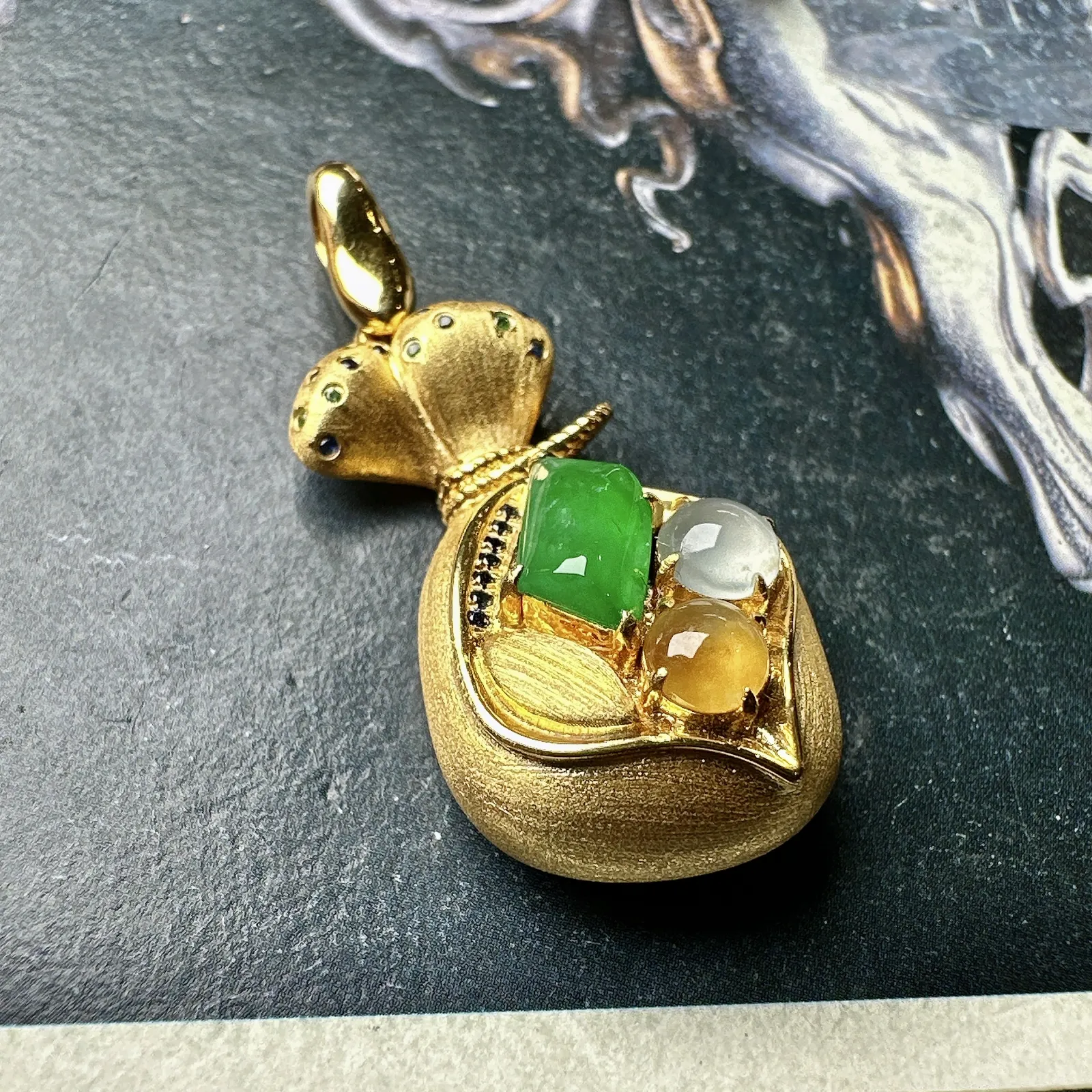 【冰种三色组合镶嵌款钱袋子】小精品。饱满度上佳，质地非常细腻，冰润通透，强胶感，强荧光，18k金钻镶嵌，其中一颗裸石尺寸9.4*5.8*3.9毫米