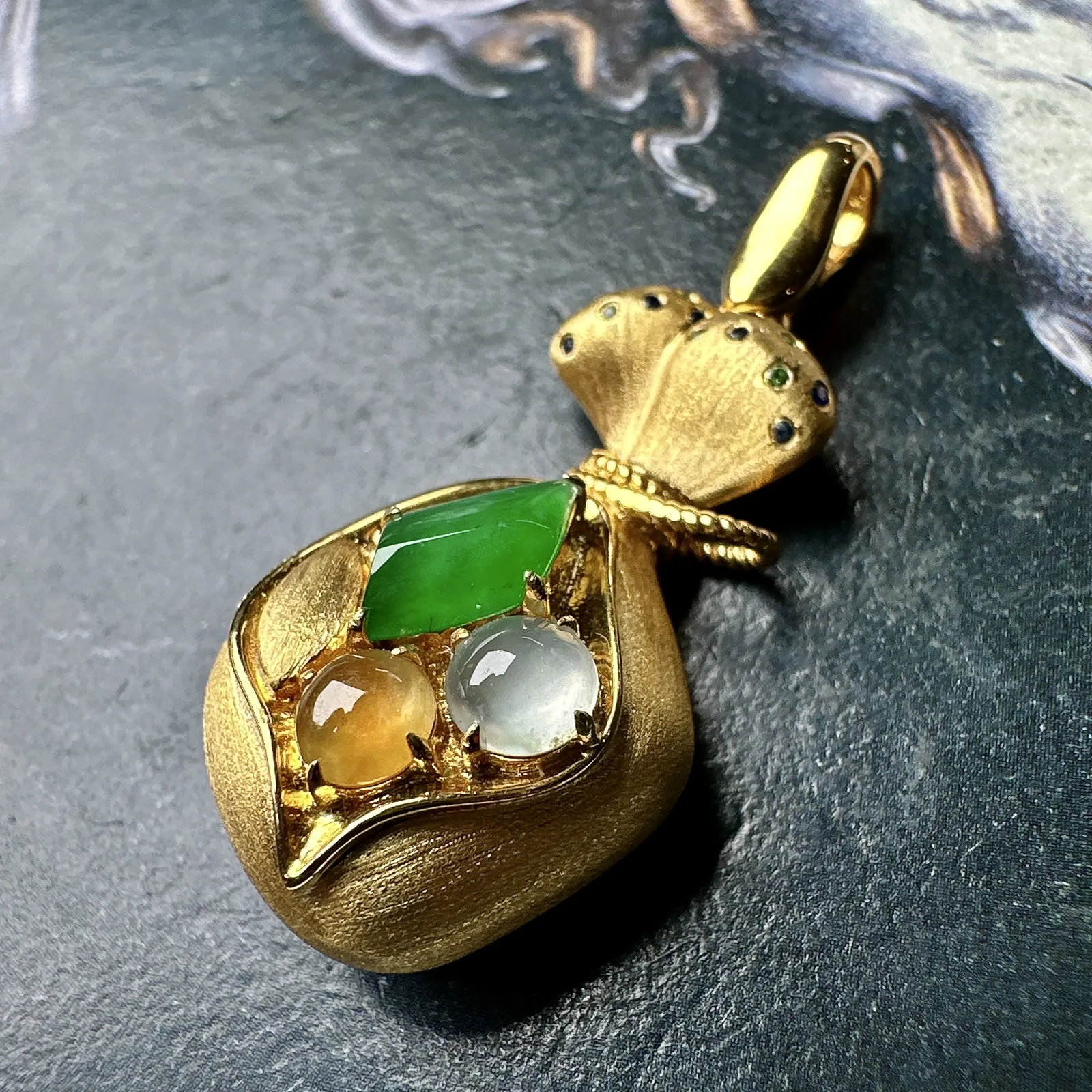 【冰种三色组合镶嵌款钱袋子】小精品。饱满度上佳，质地非常细腻，冰润通透，强胶感，强荧光，18k金钻镶嵌，其中一颗裸石尺寸9.4*5.8*3.9毫米