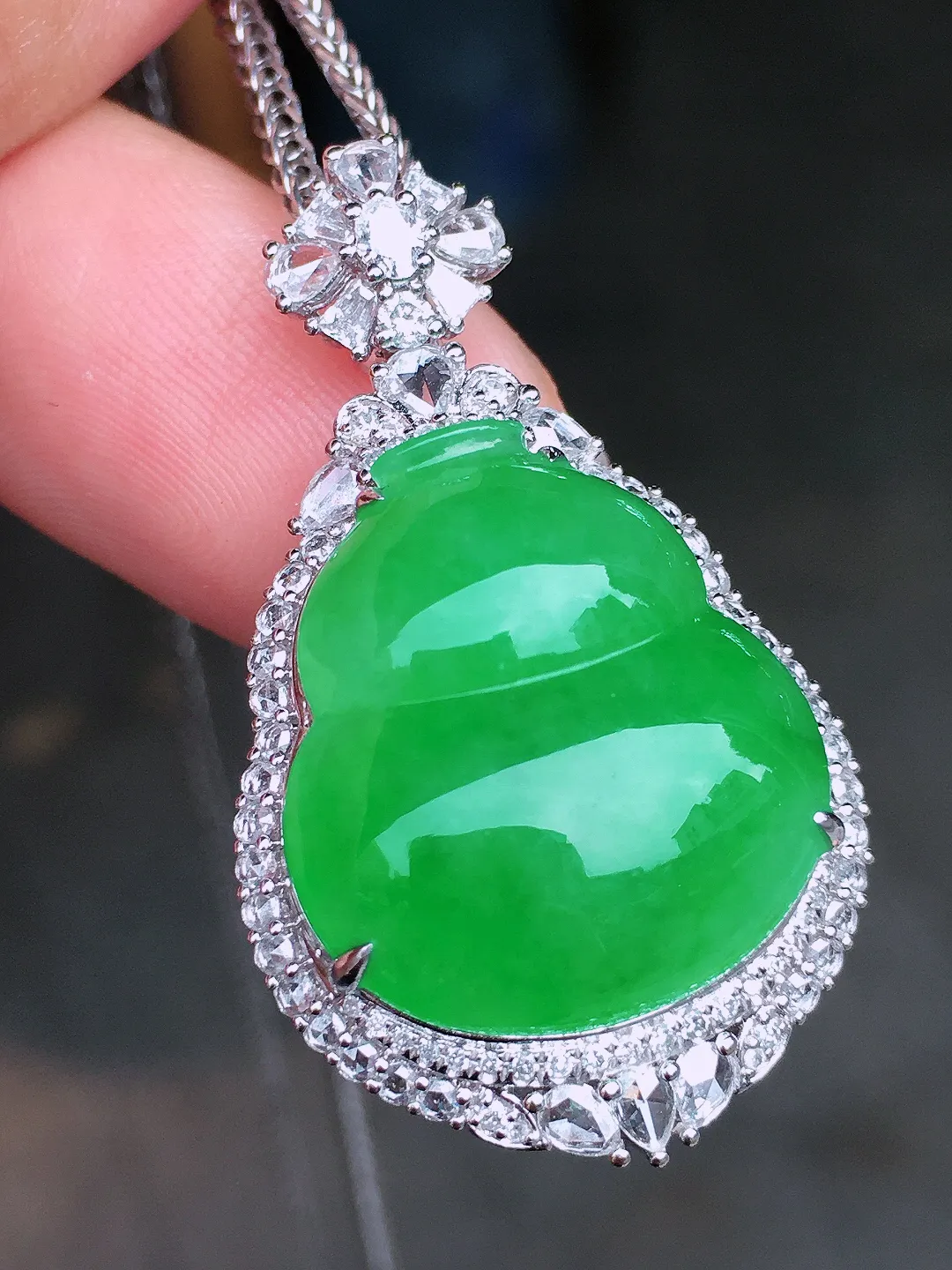 阳绿葫芦吊坠，色泽均匀艳丽，玉质细腻，荧光感超
强，饱满水润，气质满满。18k
金豪华镶嵌