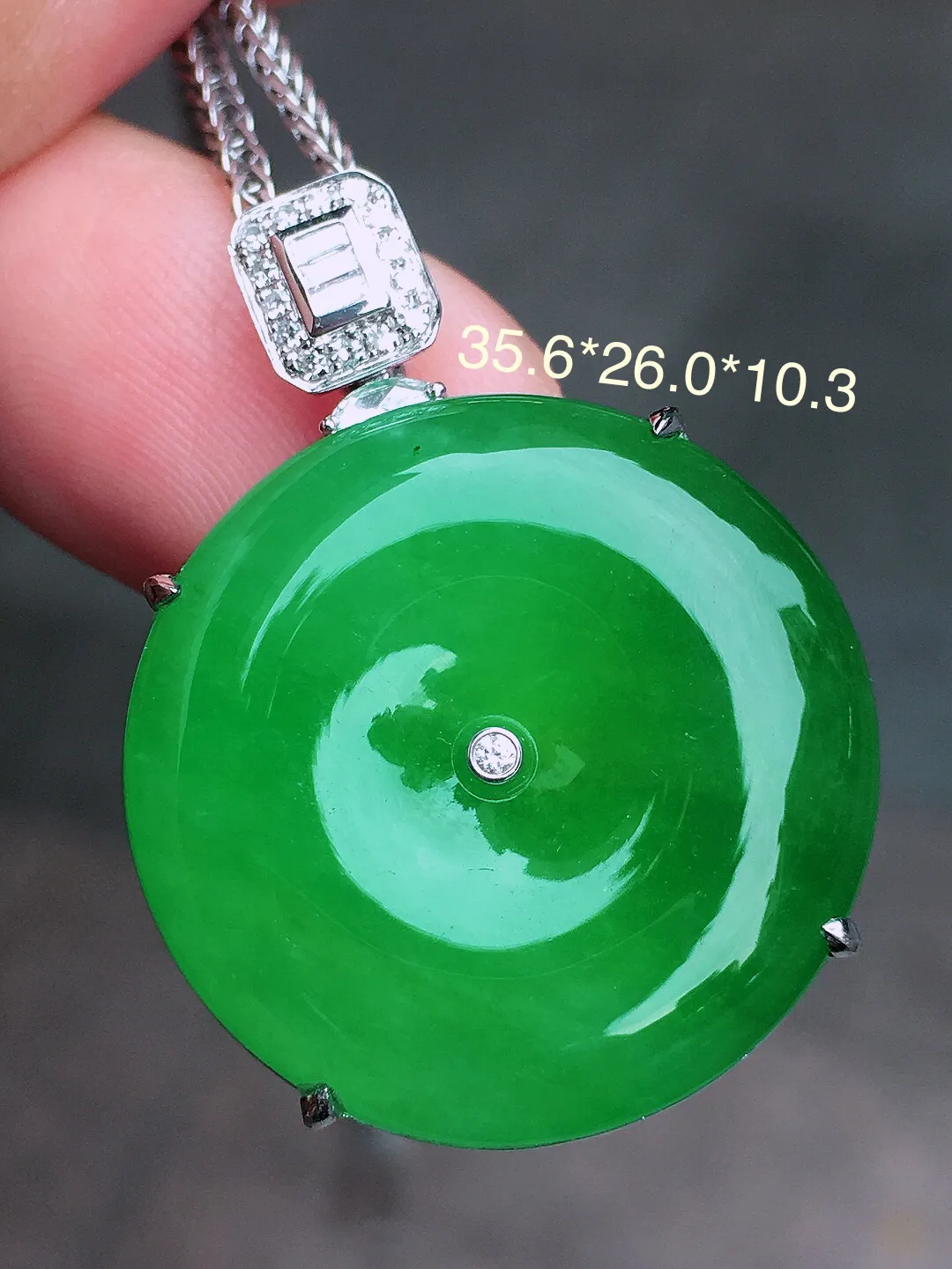 阳绿平安扣吊坠，色泽均匀艳丽，玉质细腻，荧光感超
强，饱满水润，气质满满。18k
金豪华镶嵌