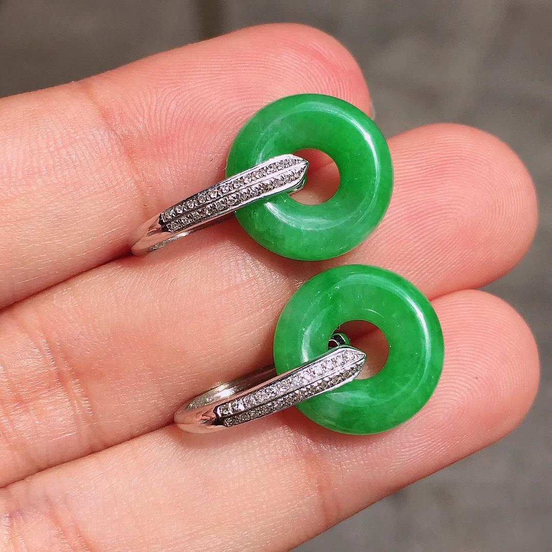 阳绿平安扣耳坠，色泽均匀艳丽，玉质细腻，荧光感超
强，饱满水润，气质满满。18k
金豪华镶嵌