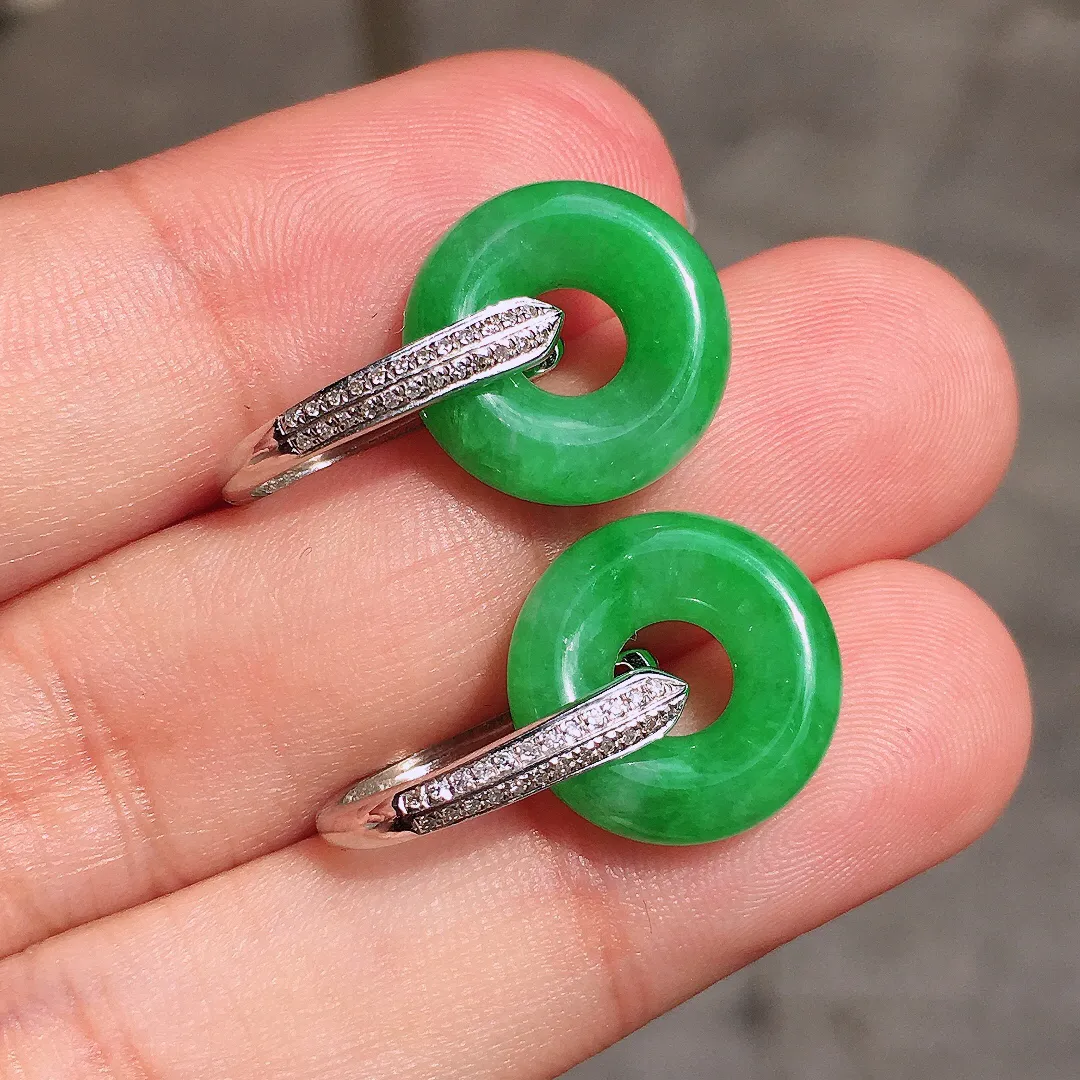 阳绿平安扣耳坠，色泽均匀艳丽，玉质细腻，荧光感超
强，饱满水润，气质满满。18k
金豪华镶嵌