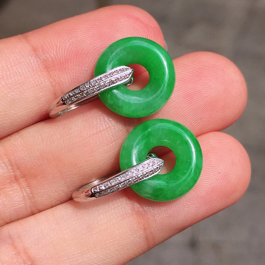 阳绿平安扣耳坠，色泽均匀艳丽，玉质细腻，荧光感超
强，饱满水润，气质满满。18k
金豪华镶嵌