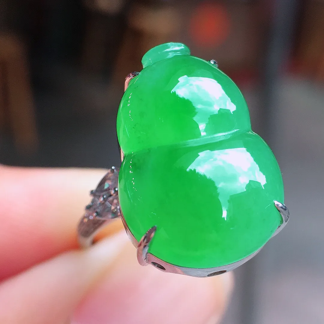 阳绿葫芦戒指，色泽均匀艳丽，玉质细腻，荧光感超
强，饱满水润，气质满满。18k
金豪华镶嵌