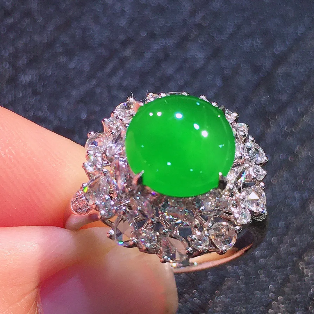 阳绿蛋面戒指，色泽均匀艳丽，玉质细腻，荧光感超
强，饱满圆润，气质满满。18k
金豪华镶嵌