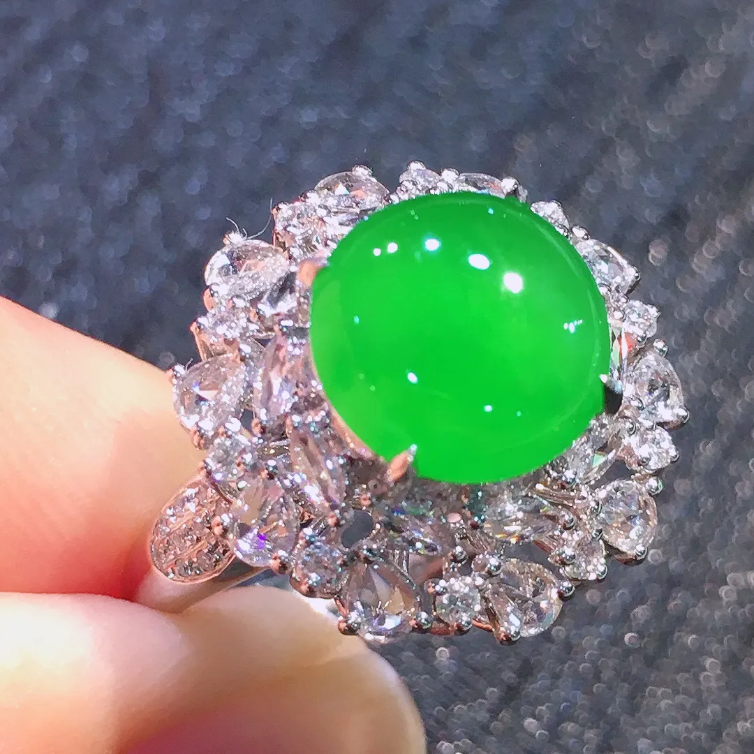 阳绿蛋面戒指，色泽均匀艳丽，玉质细腻，荧光感超
强，饱满圆润，气质满满。18k
金豪华镶嵌