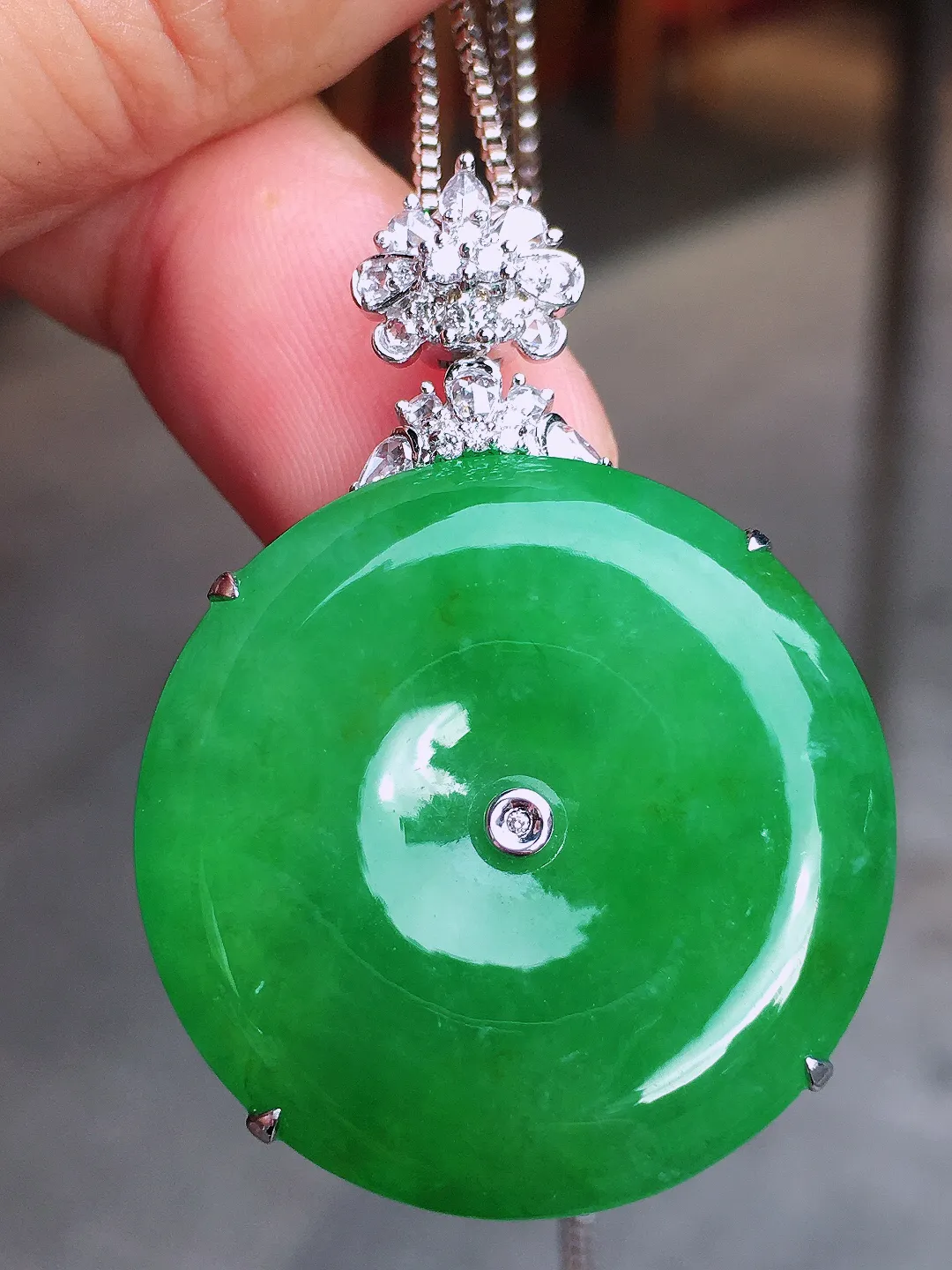 阳绿平安扣吊坠，色泽均匀艳丽，玉质细腻，荧光感超
强，饱满圆润，气质满满。18k
金豪华镶嵌