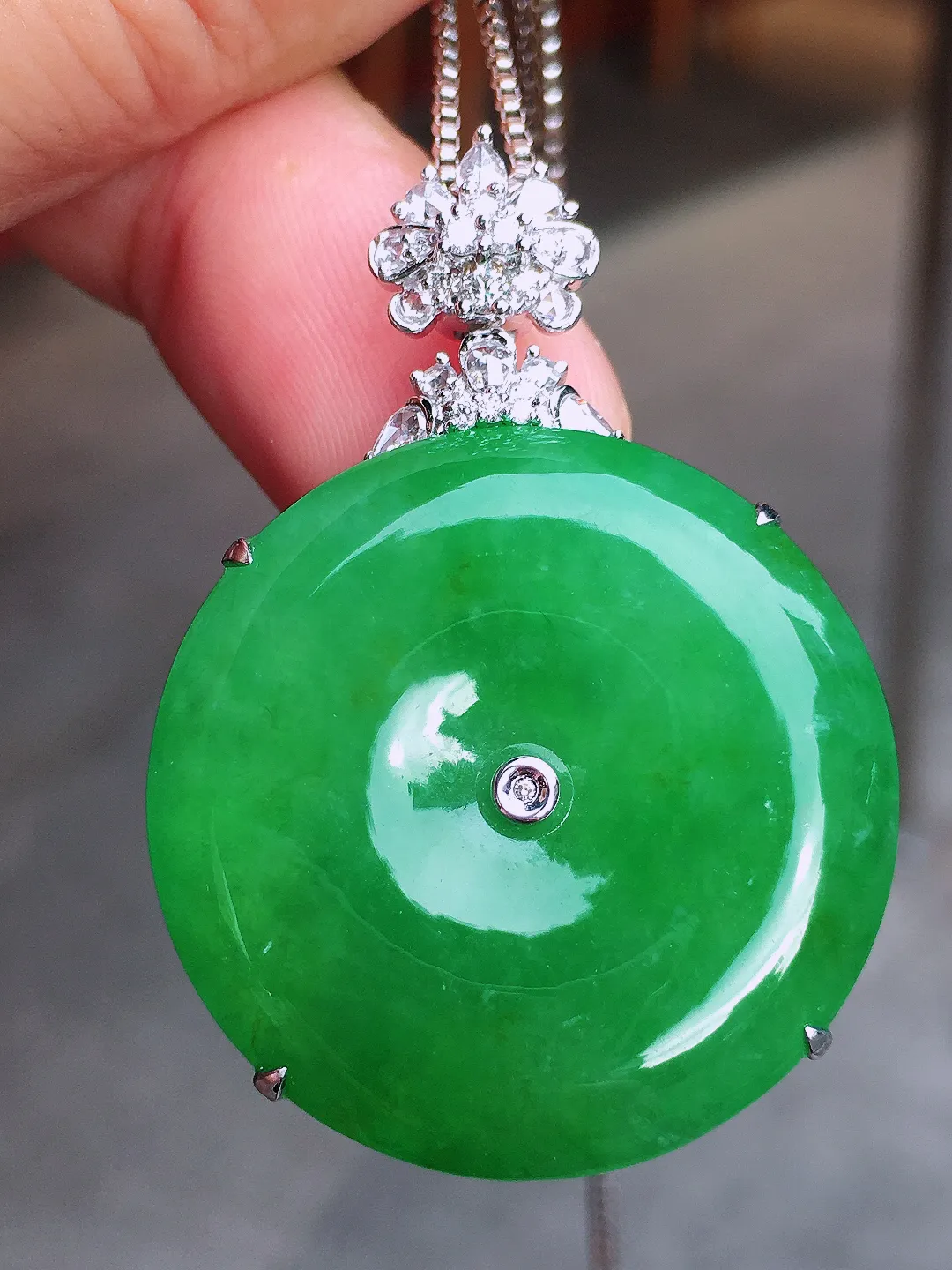 阳绿平安扣吊坠，色泽均匀艳丽，玉质细腻，荧光感超
强，饱满圆润，气质满满。18k
金豪华镶嵌