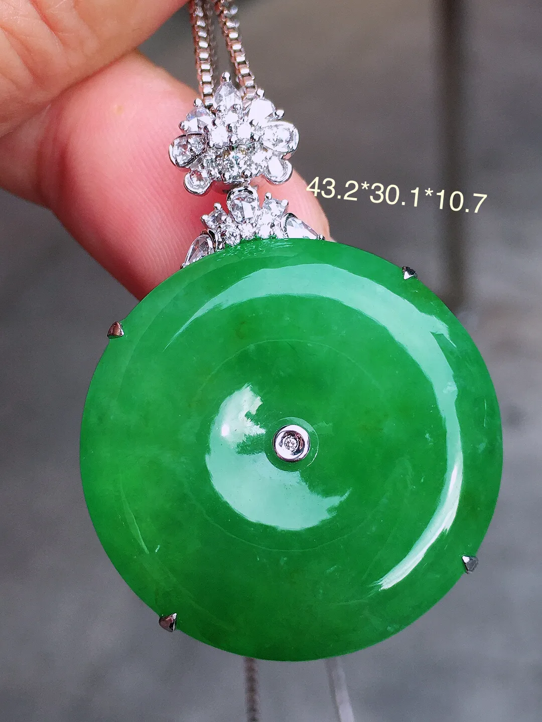 阳绿平安扣吊坠，色泽均匀艳丽，玉质细腻，荧光感超
强，饱满圆润，气质满满。18k
金豪华镶嵌