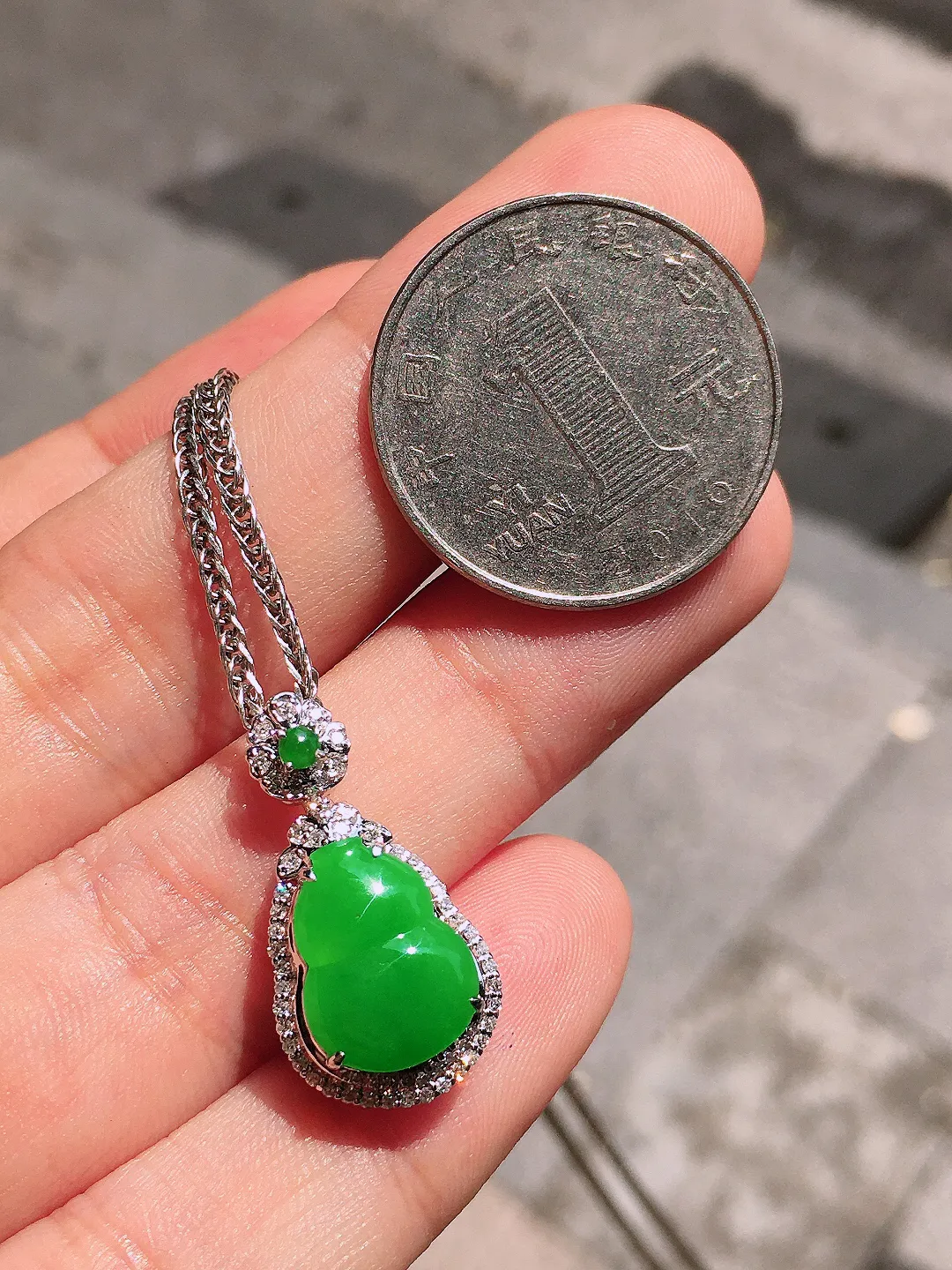 阳绿葫芦吊坠，色泽均匀艳丽，玉质细腻，荧光感超
强，饱满圆润，气质满满。18k
金豪华镶嵌