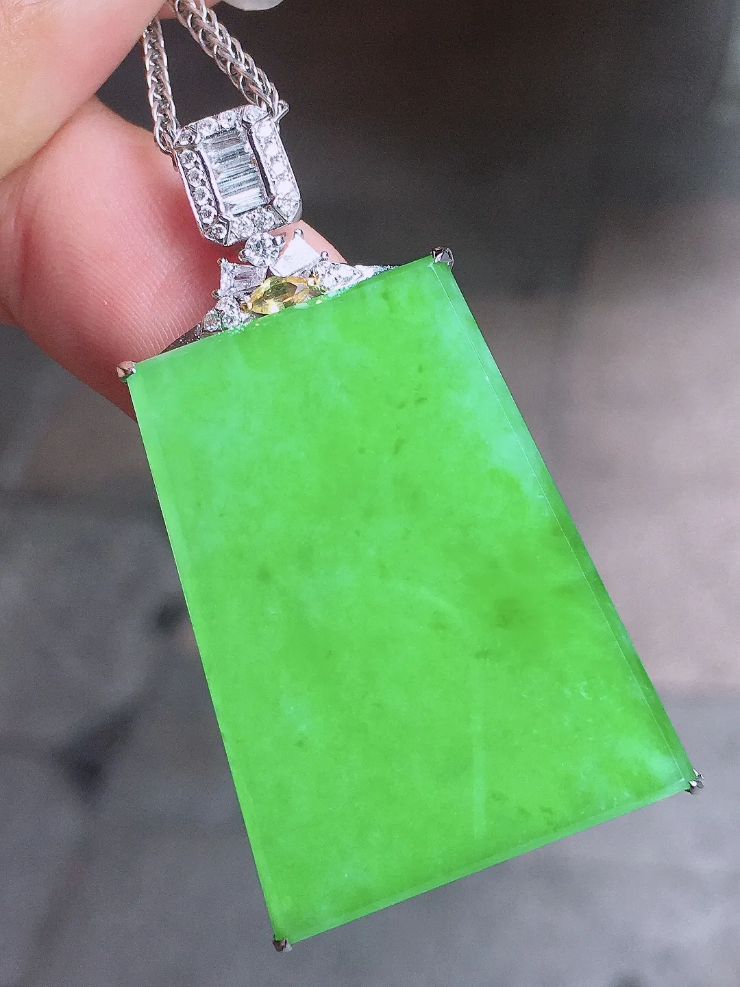 阳绿无事牌吊坠，色泽均匀艳丽，玉质细腻，荧光感超
强，饱满圆润，气质满满。18k
金豪华镶嵌