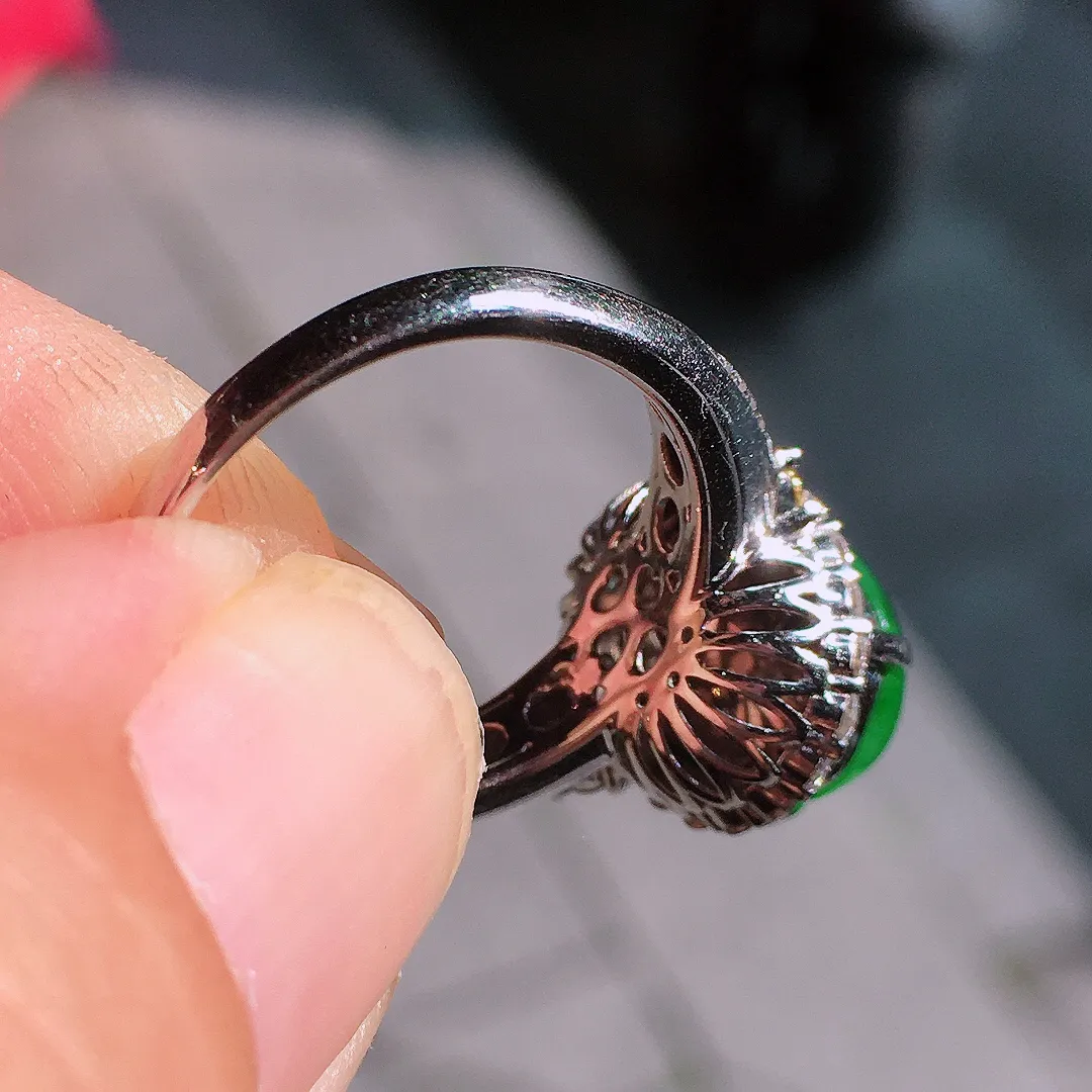 阳绿蛋面戒指，色泽均匀艳丽，玉质细腻，荧光感超
强，饱满圆润，气质满满。18k
金豪华镶嵌