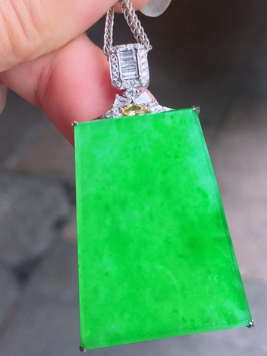 阳绿无事牌吊坠，色泽均匀艳丽，玉质细腻，荧光感超
强，饱满圆润，气质满满。18k
金豪华镶嵌