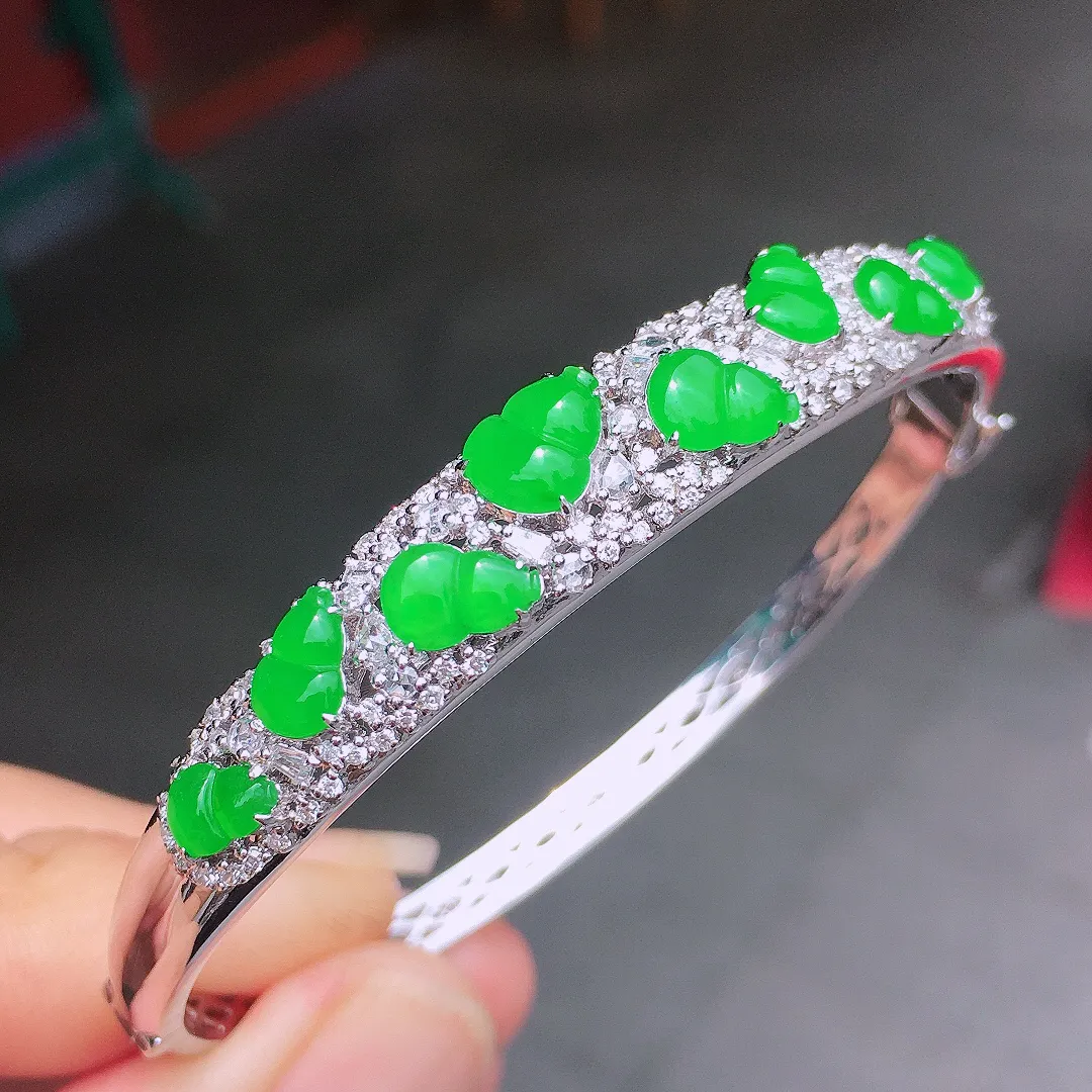 阳绿葫芦手镯，色泽均匀艳丽，玉质细腻，荧光感超
强，饱满圆润，气质满满。18k
金豪华镶嵌