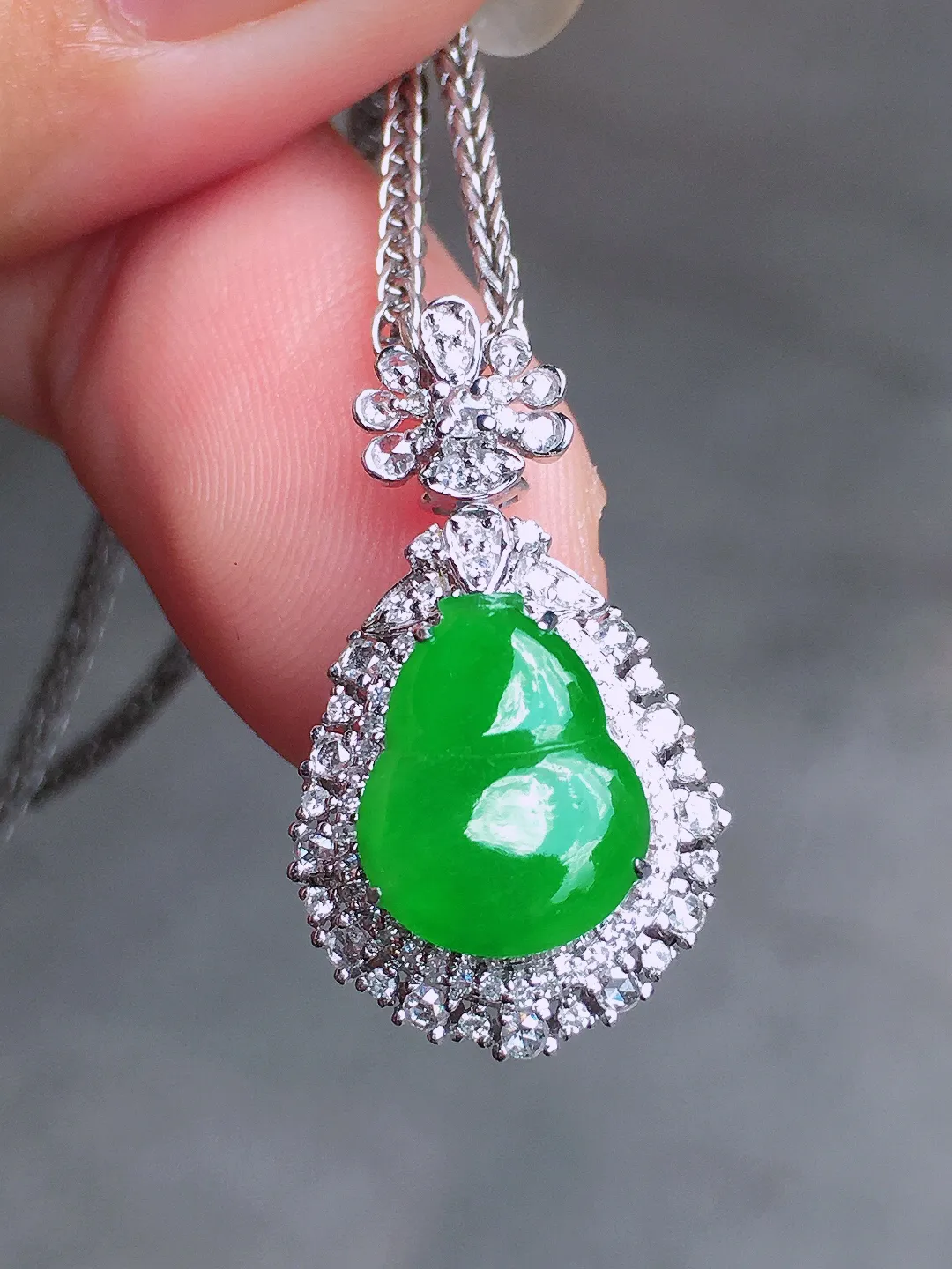 阳绿葫芦吊坠，色泽均匀艳丽，玉质细腻，荧光感超
强，饱满圆润，气质满满。18k
金豪华镶嵌