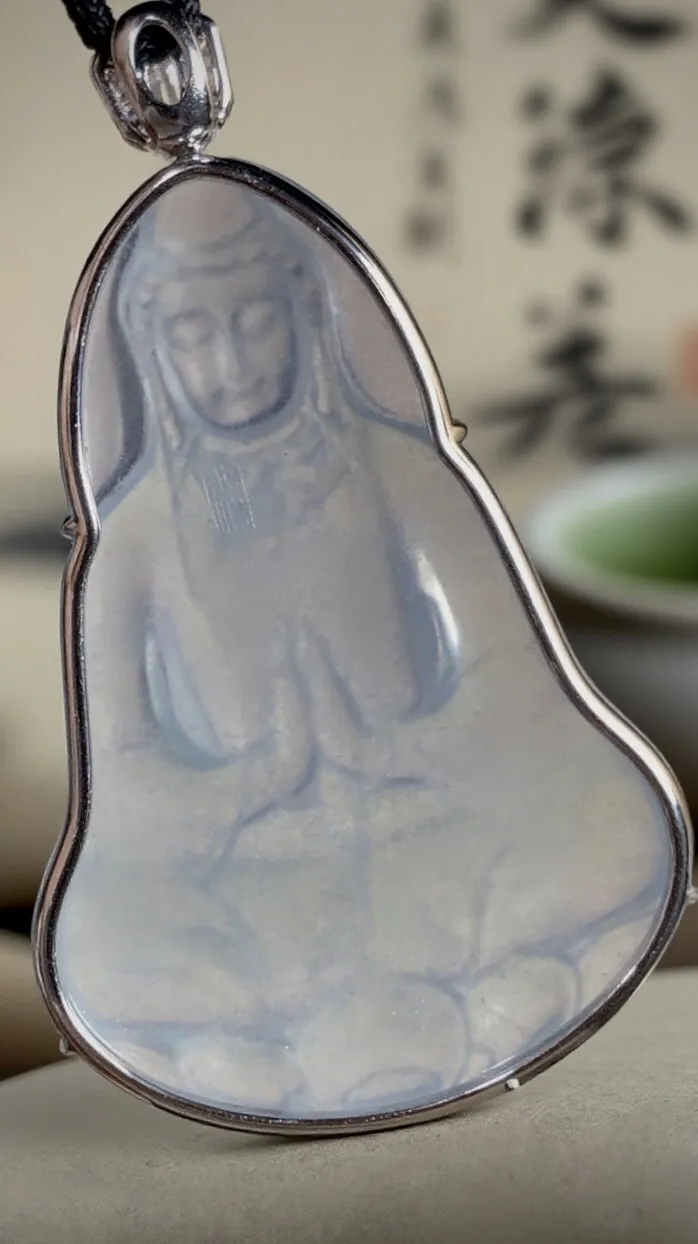 【慈悲为怀·观自在】，合十观音菩萨。
山海玉雕艺术作品，
纯白冰翡翠料子，大师雕刻，线条简约流畅，
开脸慈祥端庄，宁静温和。18K金，南非钻衬托。
作品裸石63-43-5.5mm，整体73-43-8mm。