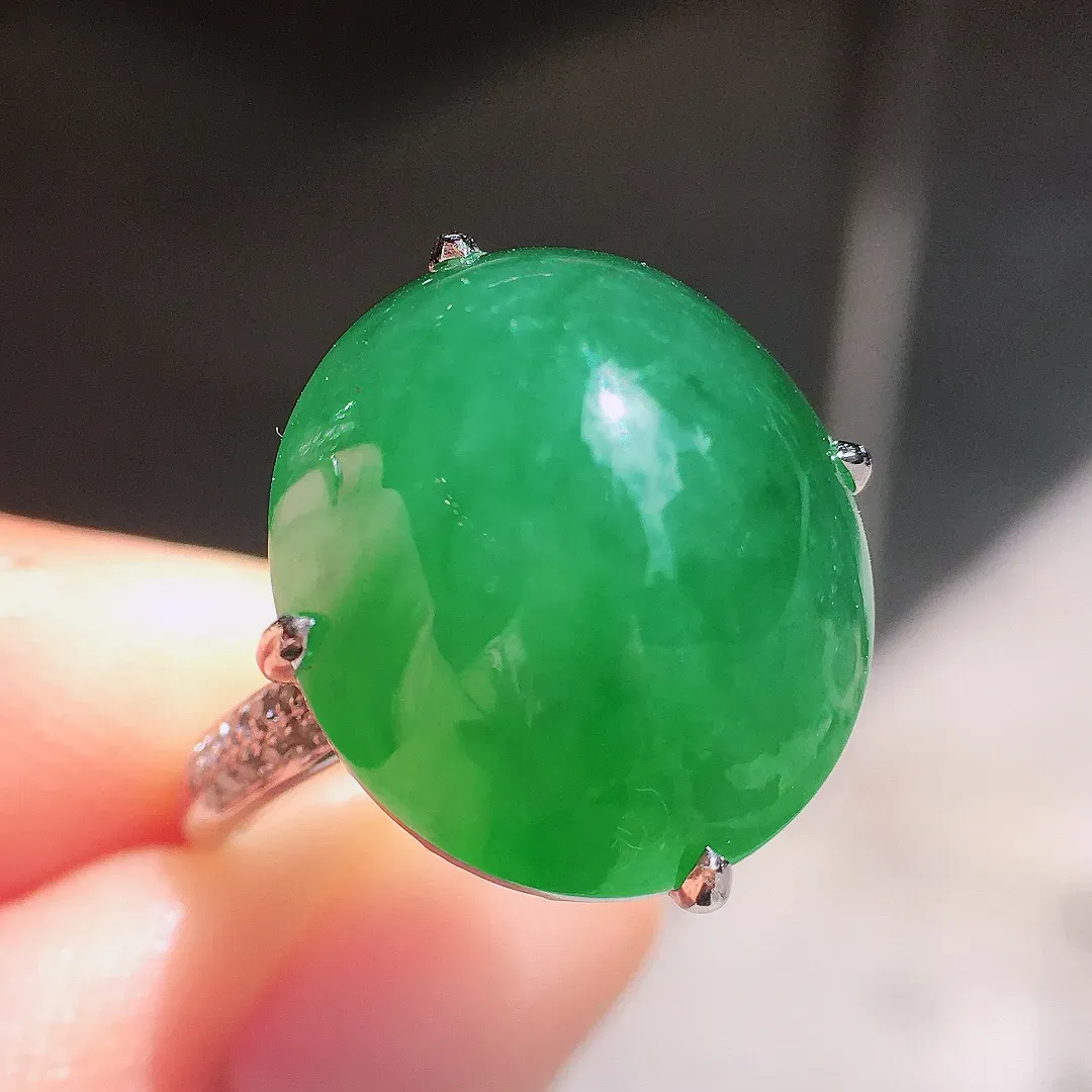 阳绿蛋面戒指，色泽均匀艳丽，玉质细腻，荧光感超
强，饱满圆润，气质满满。18k
金豪华镶嵌