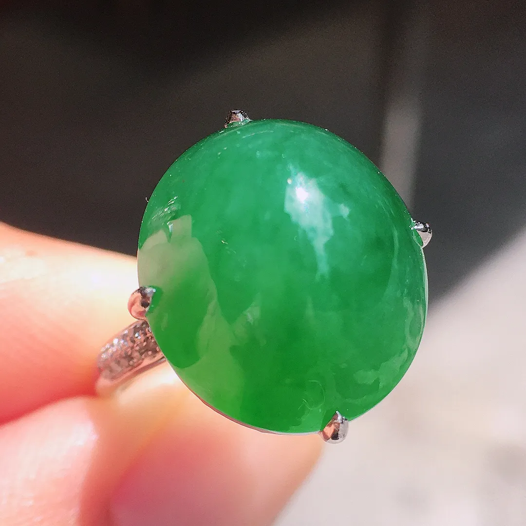 阳绿蛋面戒指，色泽均匀艳丽，玉质细腻，荧光感超
强，饱满圆润，气质满满。18k
金豪华镶嵌