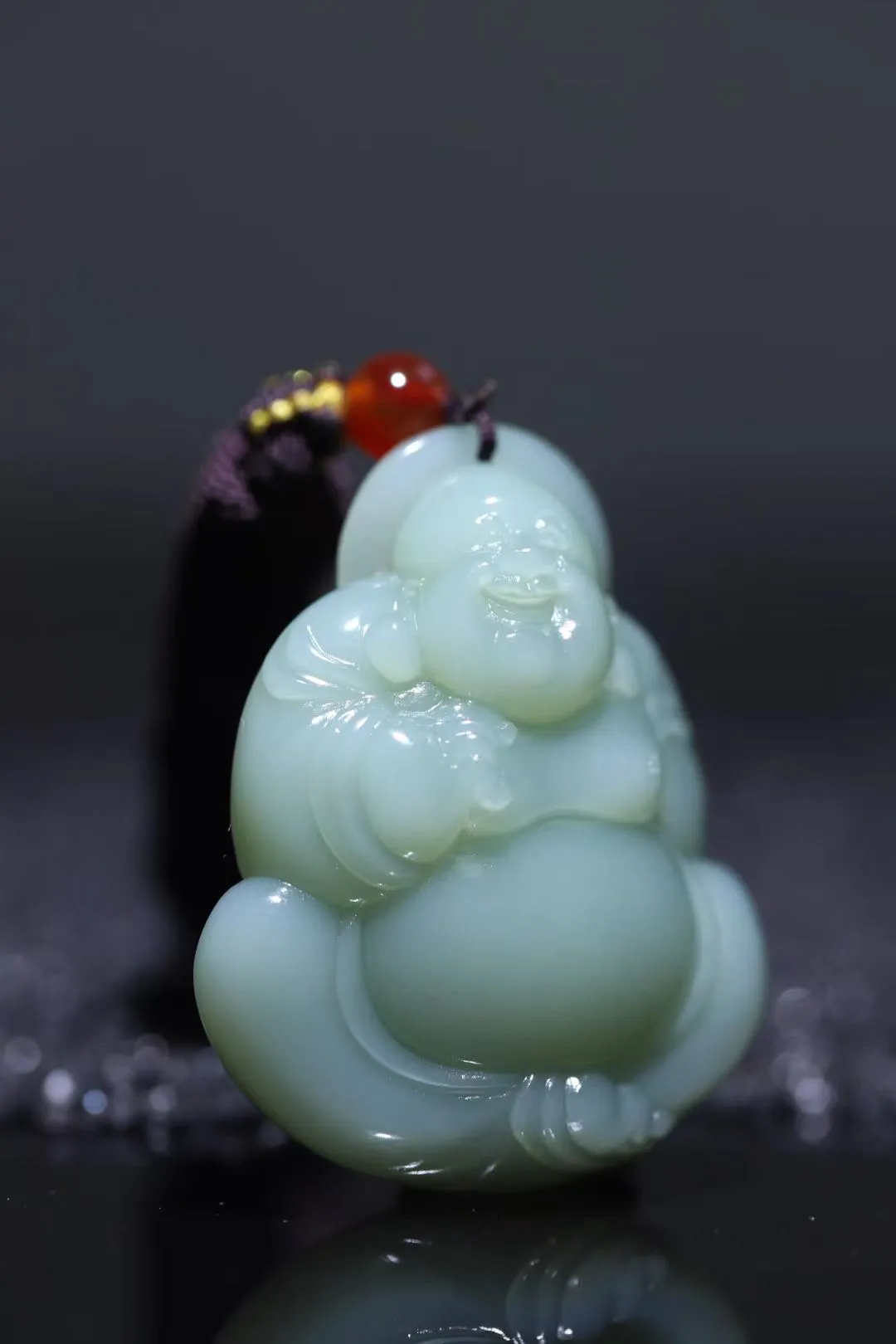禅风雅钜
【弥勒佛笑纳乾坤】和田玉精品粉青，玉质油润似膏脂初凝，触手生温若握春泉。弥勒含笑而立，衣纹流转透清雅宝光；大肚能容三江月，仰首笑破九霄云。刀工藏韵塑衣袂翩跹，眉眼弯处漾人间清欢，方寸间欢喜菩提。
【规格】43-35-13mm,28g