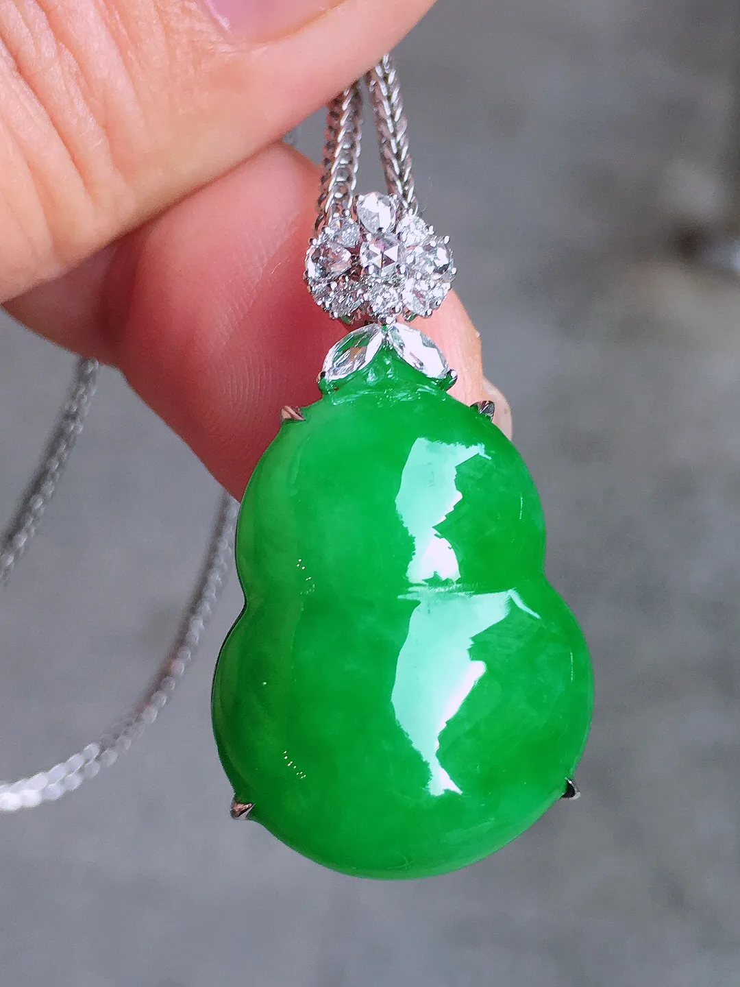 阳绿葫芦吊坠，色泽均匀艳丽，玉质细腻，荧光感超
强，饱满圆润，气质满满。18k
金豪华镶嵌