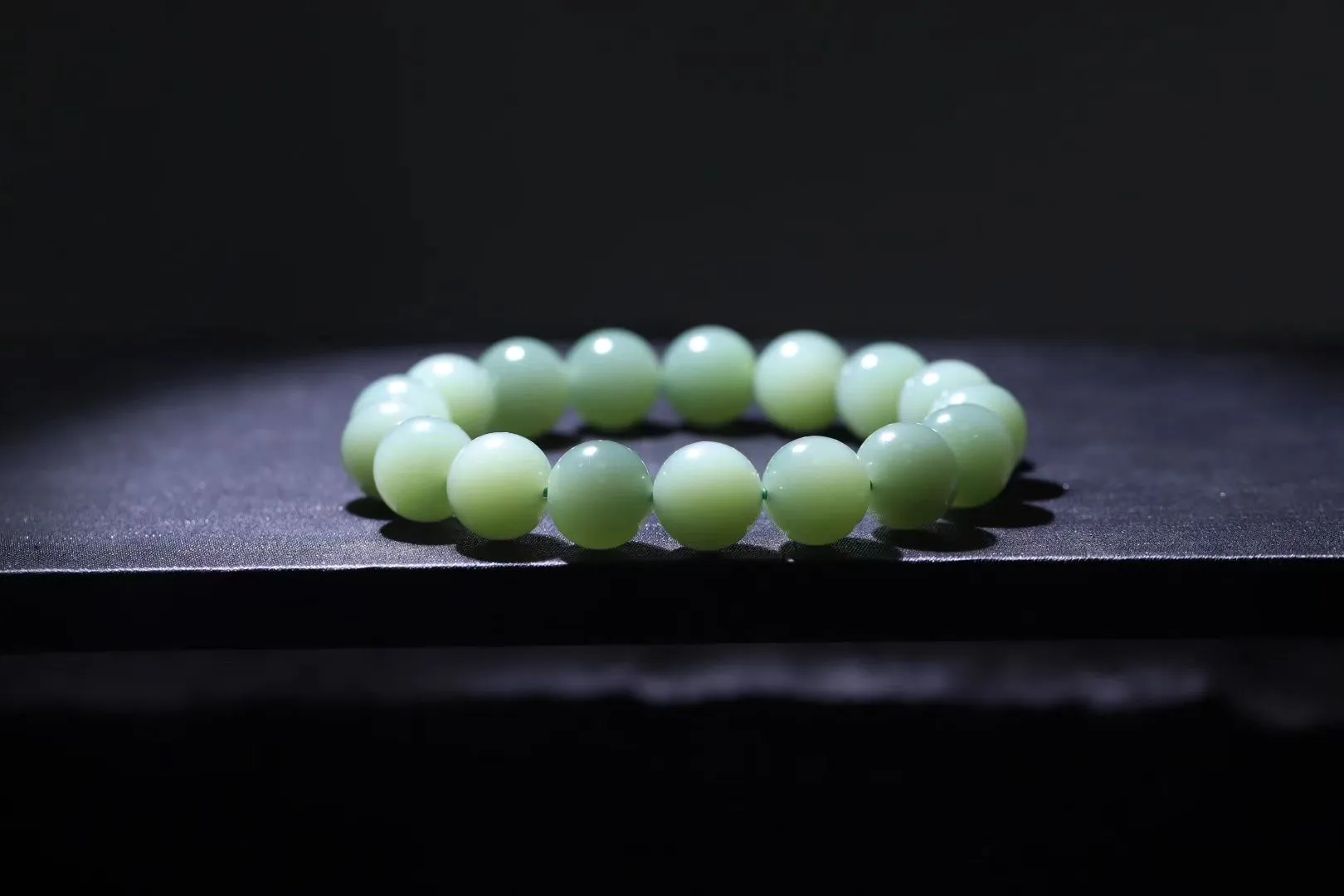 精品美物
【青霭云梦】碧玉粉青，色如初荷饮露，珠色似烟雨漫过江南岸。颗颗正圆蕴月华之形，温润入手若握一捧泠泠春水，清光流转间肌理隐现冰绢纹。此串不争浓艳，独倚素影写空灵，绾于腕上恰似裁取碧落云絮三分，佩者自生林下风致。
【规格】珠径12mm，49g