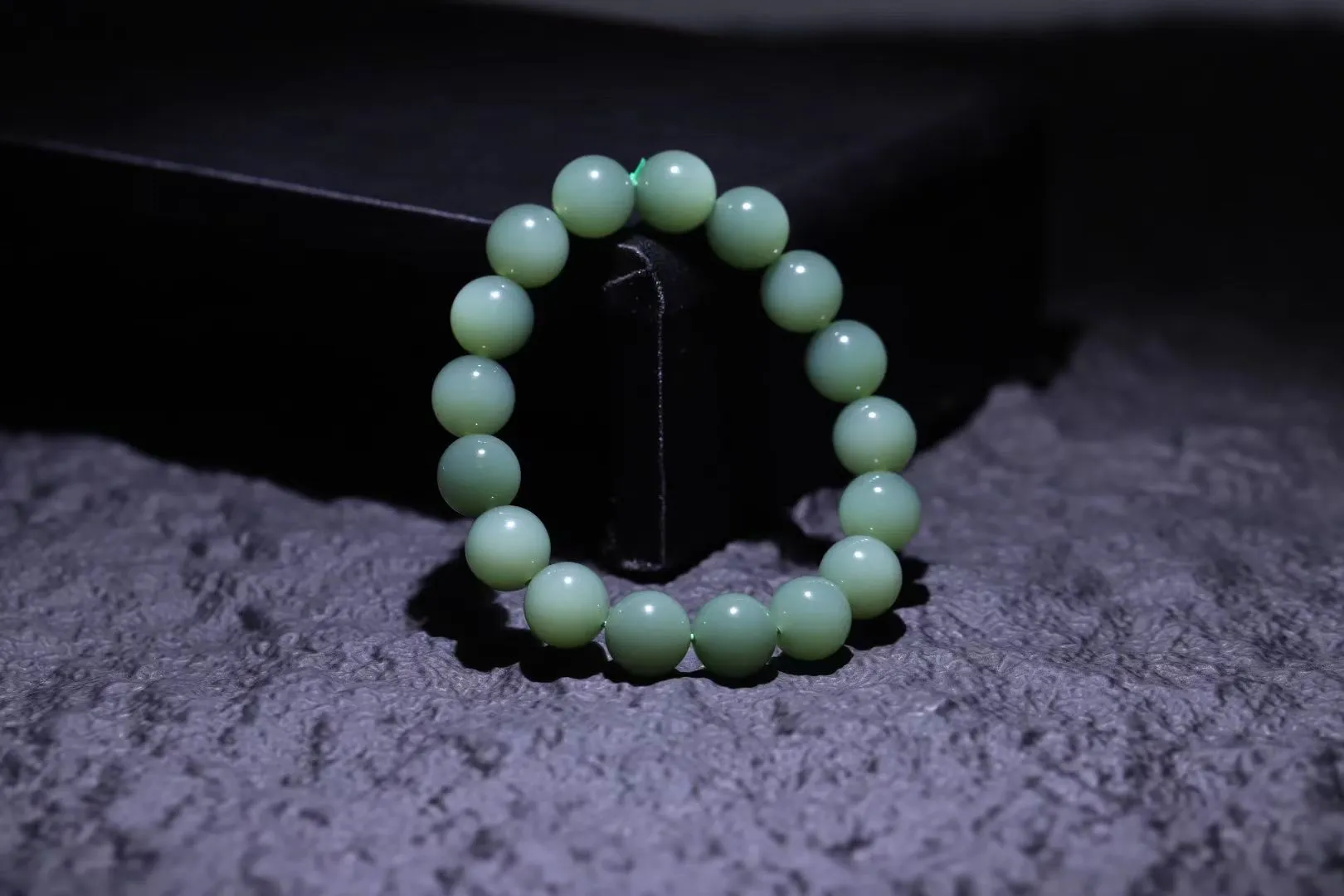 精品美物
【青霭云梦】碧玉粉青，色如初荷饮露，珠色似烟雨漫过江南岸。颗颗正圆蕴月华之形，温润入手若握一捧泠泠春水，清光流转间肌理隐现冰绢纹。此串不争浓艳，独倚素影写空灵，绾于腕上恰似裁取碧落云絮三分，佩者自生林下风致。
【规格】珠径12mm，49g