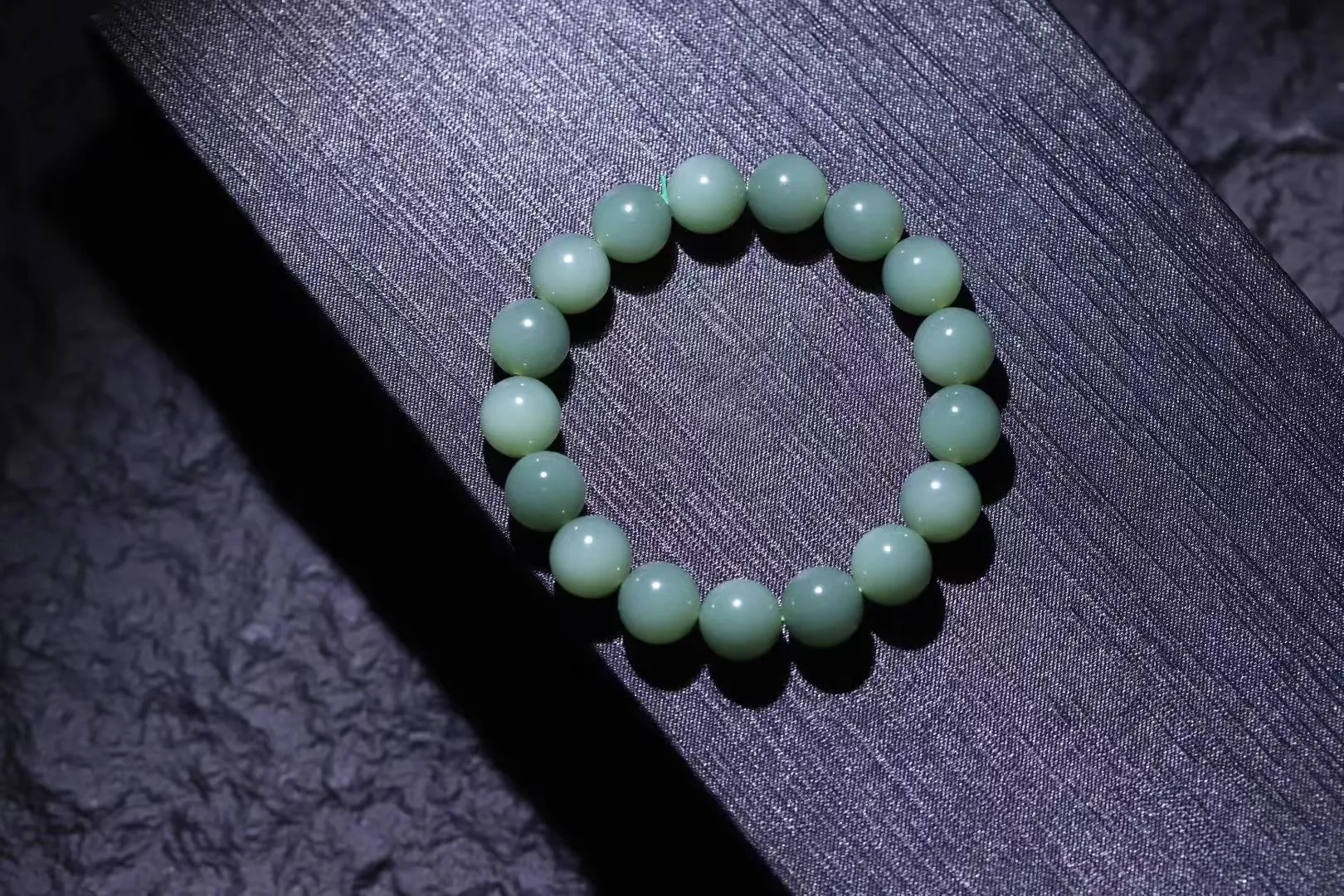 精品美物
【青霭云梦】碧玉粉青，色如初荷饮露，珠色似烟雨漫过江南岸。颗颗正圆蕴月华之形，温润入手若握一捧泠泠春水，清光流转间肌理隐现冰绢纹。此串不争浓艳，独倚素影写空灵，绾于腕上恰似裁取碧落云絮三分，佩者自生林下风致。
【规格】珠径12mm，49g