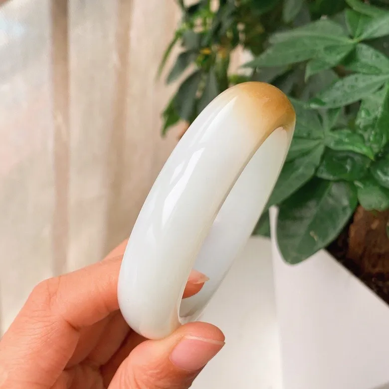 59圈口。新疆和田玉且末糖羊脂白玉手镯。且末糖一口糖手镯。圈口59条宽17厚10重89.9克。白度一级。玉质细腻油润。无裂无杂。手推出油。品相大气。 lt251013