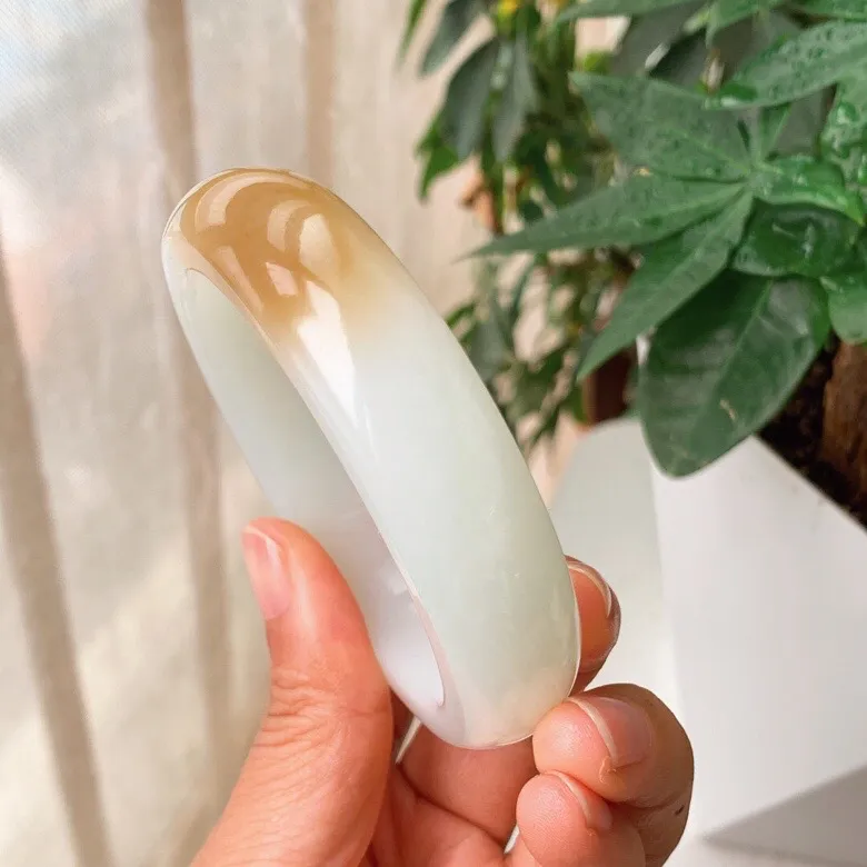 59圈口。新疆和田玉且末糖羊脂白玉手镯。且末糖一口糖手镯。圈口59条宽17厚10重89.9克。白度一级。玉质细腻油润。无裂无杂。手推出油。品相大气。 lt251013