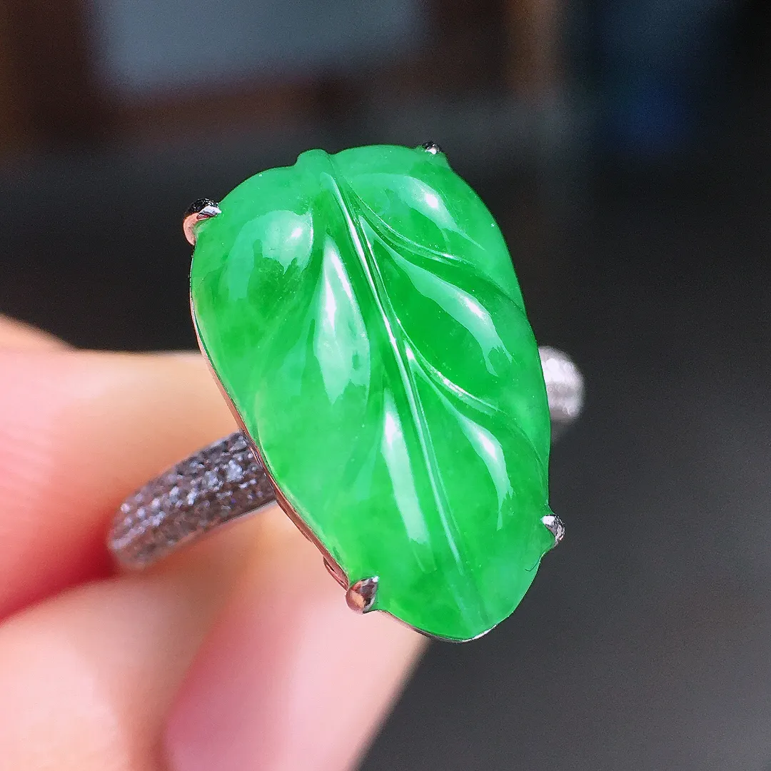 阳绿玉叶戒指，色泽均匀艳丽，玉质细腻，荧光感超
强，饱满圆润，尽显优雅气质，18k
金豪华镶嵌