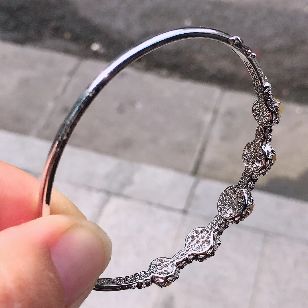 黄翡蛋面手镯，色泽均匀艳丽，玉质细腻，荧光感超
强，饱满圆润，尽显优雅气质，18k
金豪华镶嵌