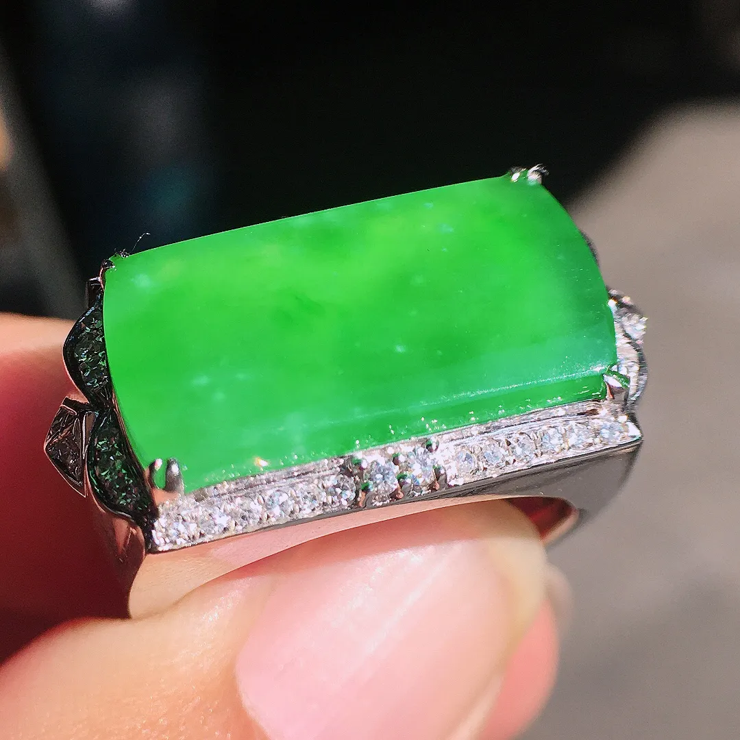 阳绿马鞍戒指，色泽均匀艳丽，玉质细腻，荧光感超
强，饱满圆润，尽显优雅气质，18k
金豪华镶嵌