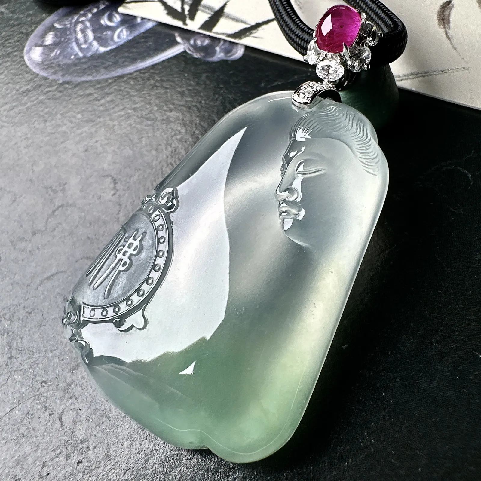 【冰种观音首吊坠】侧面像，料子通透闪亮，质地致密，种老起强胶感，玻璃光泽强烈。人物面部开脸生动，雕刻很精细，表情端庄祥和。料子纯净，18K金钻精美镶嵌，裸石尺寸44.2*31.2*10.7毫米