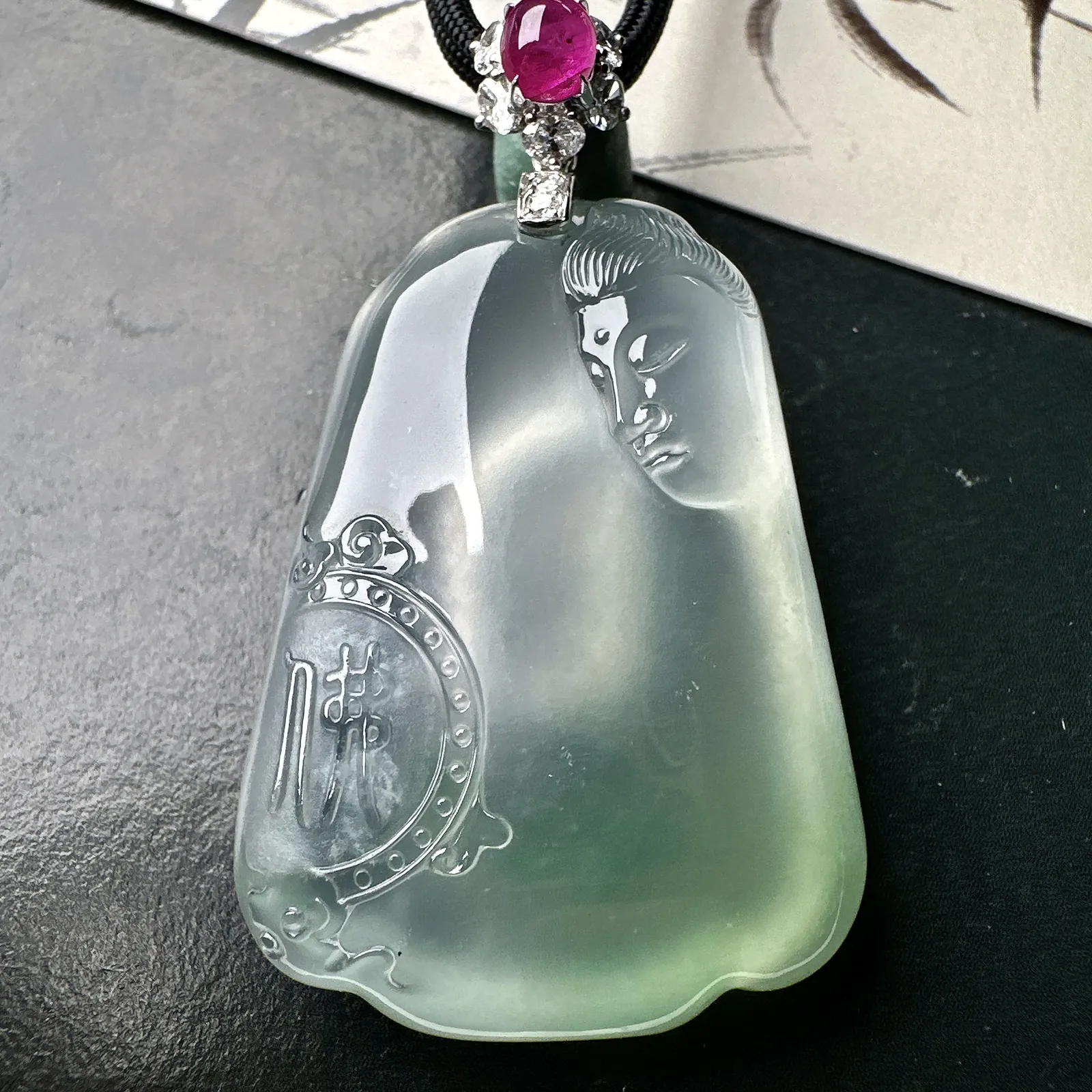 【冰种观音首吊坠】侧面像，料子通透闪亮，质地致密，种老起强胶感，玻璃光泽强烈。人物面部开脸生动，雕刻