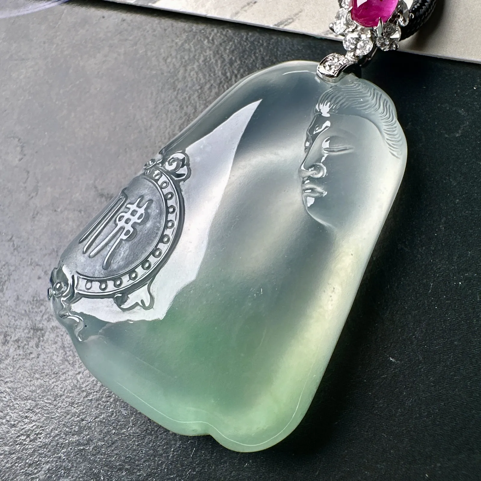 【冰种观音首吊坠】侧面像，料子通透闪亮，质地致密，种老起强胶感，玻璃光泽强烈。人物面部开脸生动，雕刻很精细，表情端庄祥和。料子纯净，18K金钻精美镶嵌，裸石尺寸44.2*31.2*10.7毫米