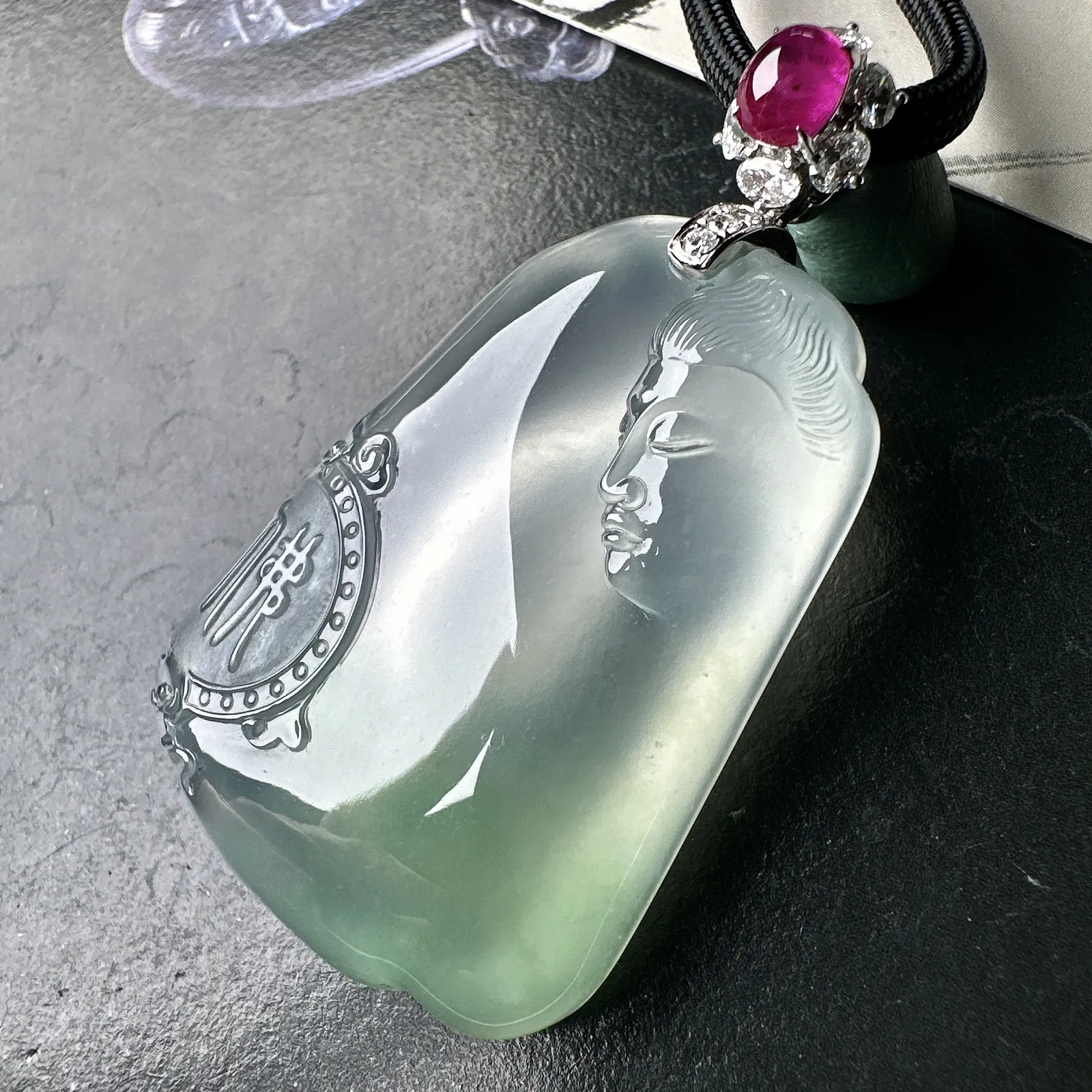 【冰种观音首吊坠】侧面像，料子通透闪亮，质地致密，种老起强胶感，玻璃光泽强烈。人物面部开脸生动，雕刻很精细，表情端庄祥和。料子纯净，18K金钻精美镶嵌，裸石尺寸44.2*31.2*10.7毫米