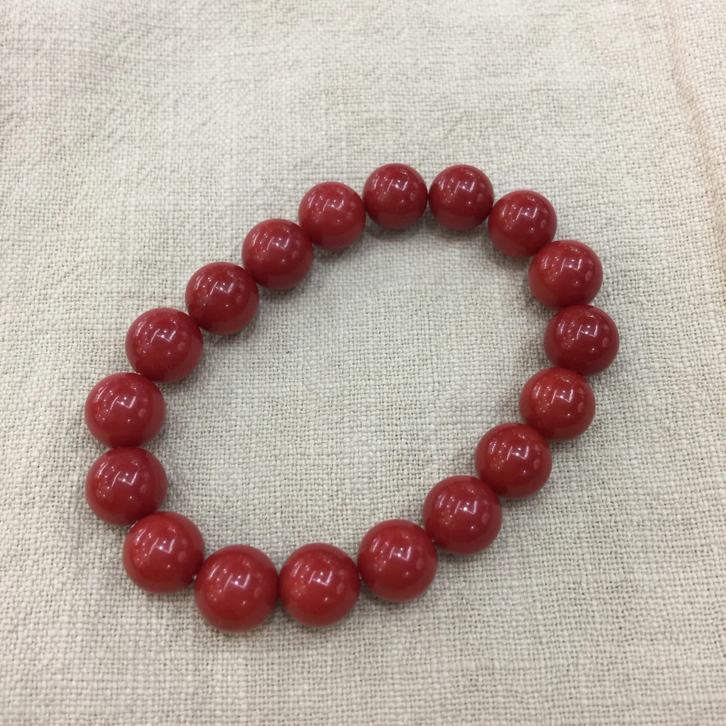 【天然近牛血珊瑚10mm大圆珠弹力手串】近牛血红颜色，光泽柔润透亮，直径约为10.15-9.36mm，重量为23.48克，珊瑚本为佛教珍宝，来自深海千年生长，有生长纹，属于有机宝石，气场强大，材料意大利沙丁材料，稀少珍贵！每粒均为天然无添加无修补！收藏精品！传承宝贝！