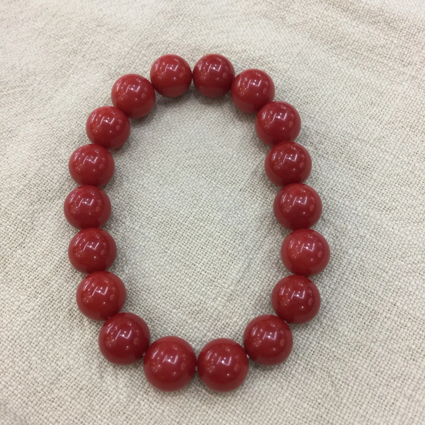 【天然近牛血珊瑚10mm大圆珠弹力手串】近牛血红颜色，光泽柔润透亮，直径约为10.15-9.36mm，重量为23.48克，珊瑚本为佛教珍宝，来自深海千年生长，有生长纹，属于有机宝石，气场强大，材料意大利沙丁材料，稀少珍贵！每粒均为天然无添加无修补！收藏精品！传承宝贝！