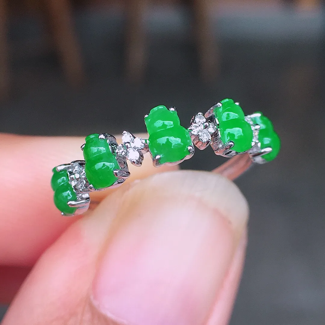 阳绿葫芦排戒指，色泽均匀艳丽，玉质细腻，荧光感超
强，饱满圆润，尽显优雅气质，18k
金豪华镶嵌