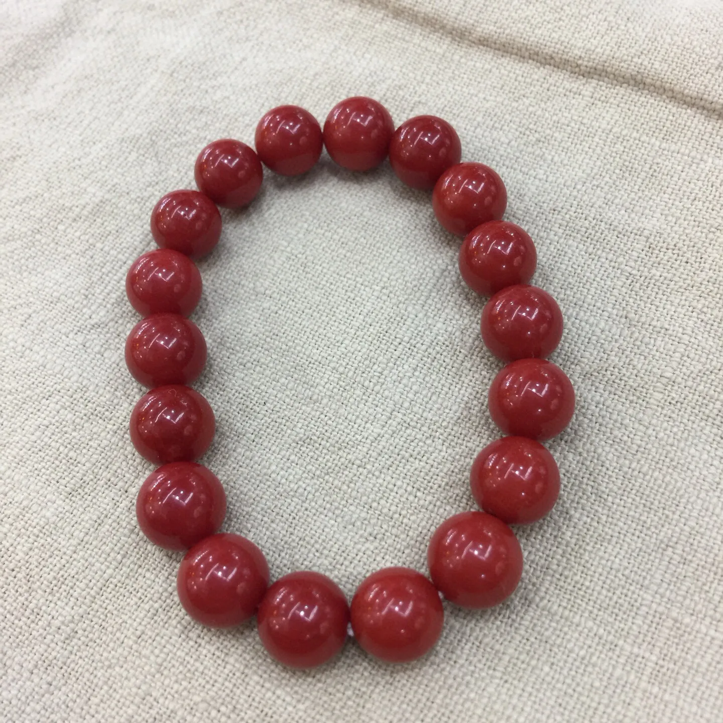 【天然近牛血珊瑚10mm大圆珠弹力手串】近牛血红颜色，光泽柔润透亮，直径约为10.15-9.36mm，重量为23.48克，珊瑚本为佛教珍宝，来自深海千年生长，有生长纹，属于有机宝石，气场强大，材料意大利沙丁材料，稀少珍贵！每粒均为天然无添加无修补！收藏精品！传承宝贝！