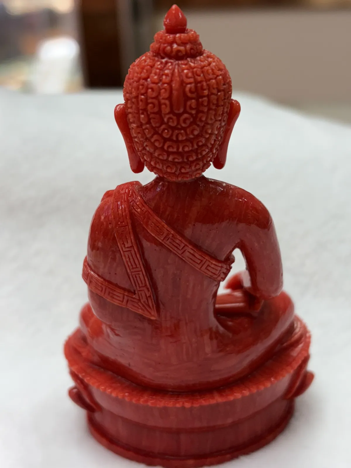 【红珊瑚释迦牟尼佛中号佛像摆件】佛祖庄严肃穆，佛像顶结高肉螺髻，髻顶可见顶严，双耳垂肩，脸型清秀，双眉高挑，高鼻细挺，身着袒右式袈裟，左手持钵，裸双足结跏趺坐于莲台之上，莲台高起，饰有饱满的连珠纹，底部有开孔，可藏经文珠宝等，材料为天然意大利沙丁，台湾拼接工艺，做工精良，裸石尺寸110*63.7*43.6mm，重量120.25克。