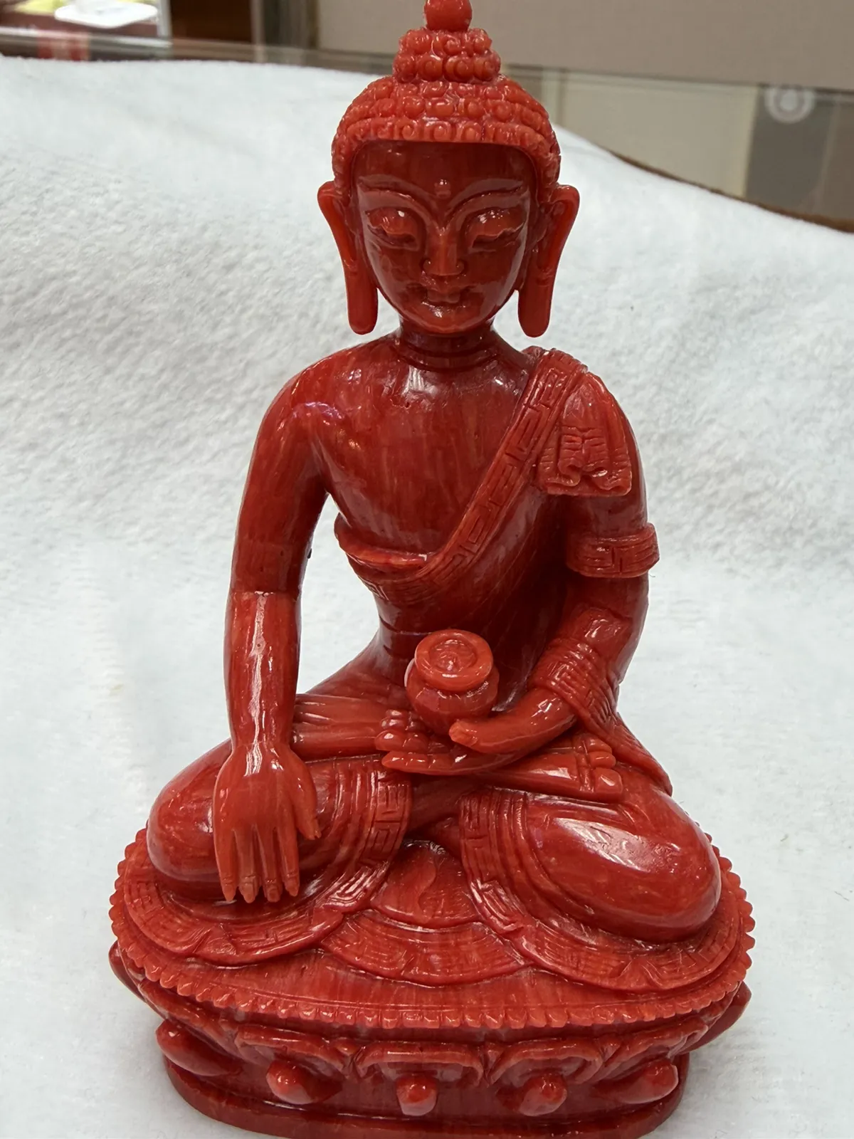 【红珊瑚释迦牟尼佛中号佛像摆件】佛祖庄严肃穆，佛像顶结高肉螺髻，髻顶可见顶严，双耳垂肩，脸型清秀，双眉高挑，高鼻细挺，身着袒右式袈裟，左手持钵，裸双足结跏趺坐于莲台之上，莲台高起，饰有饱满的连珠纹，底部有开孔，可藏经文珠宝等，材料为天然意大利沙丁，台湾拼接工艺，做工精良，裸石尺寸110*63.7*43.6mm，重量120.25克。