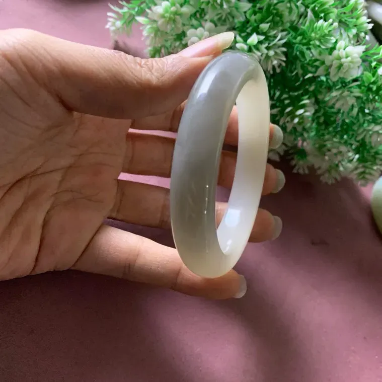 59.5圈口和田玉白加紫色手镯【挽间柔情】，镯型古朴典雅。在诗情画意的雨巷相遇，你是我腕间的一抹风情，有你眸有深情.清风荡漾湖间静水，我愿俯身低眉，在烟波涟漪处寻你。规格59.5/13.5