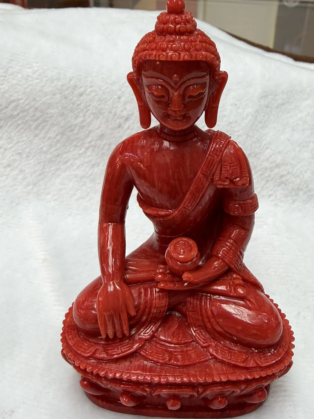 【红珊瑚释迦牟尼佛中号佛像摆件】佛祖庄严肃穆，佛像顶结高肉螺髻，髻顶可见顶严，双耳垂肩，脸型清秀，双眉高挑，高鼻细挺，身着袒右式袈裟，左手持钵，裸双足结跏趺坐于莲台之上，莲台高起，饰有饱满的连珠纹，底部有开孔，可藏经文珠宝等，材料为天然意大利沙丁，台湾拼接工艺，做工精良，裸石尺寸110*63.7*43.6mm，重量120.25克。
